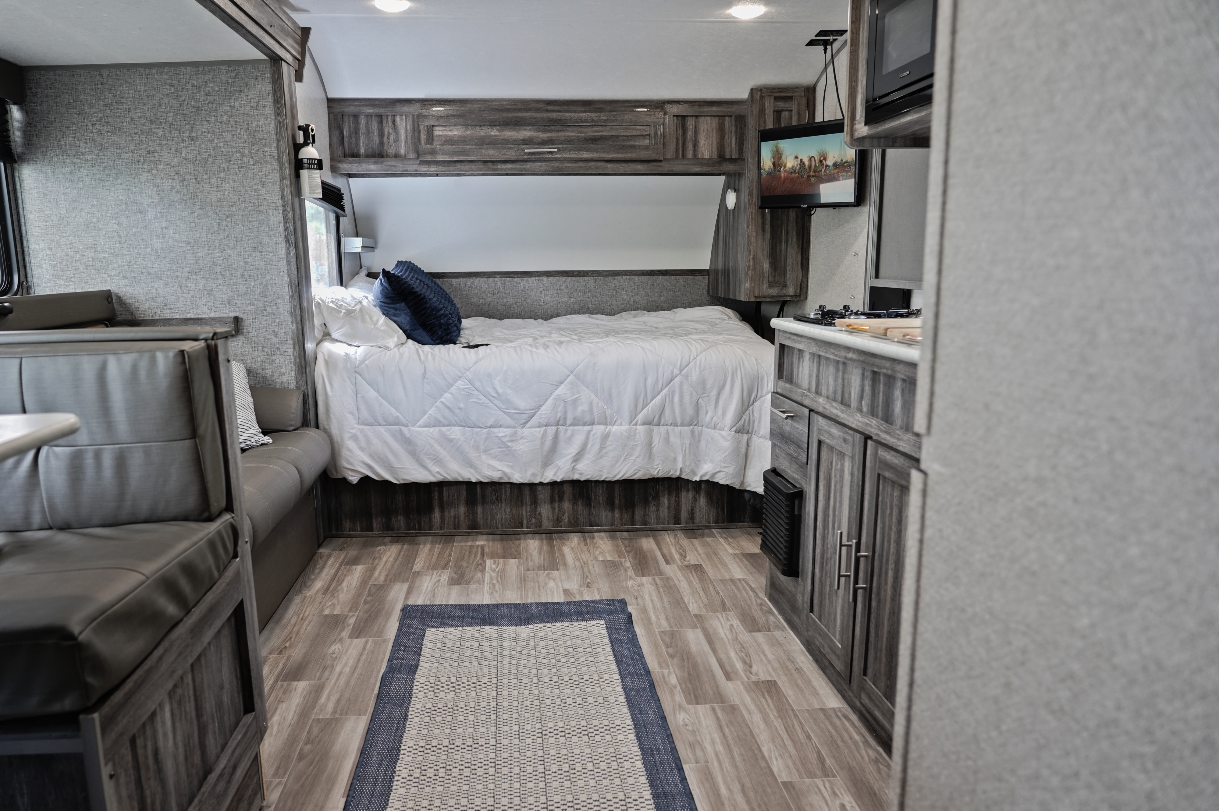 Spacious RV rental interior featuring a cozy bed, compact kitchen, and dinette area for comfortable travels.. Forest River Wildwood FSX 2020