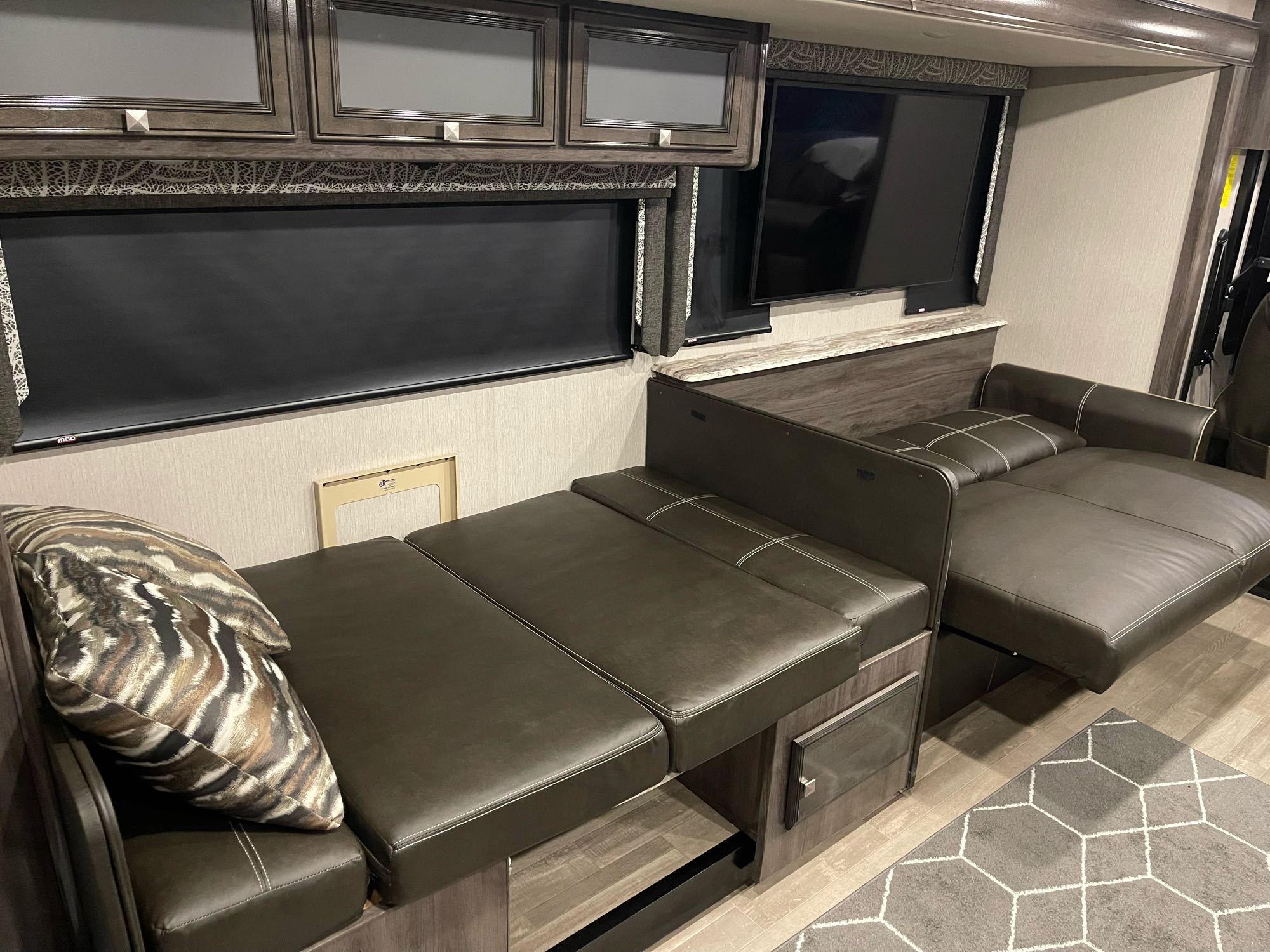 Spacious RV rental interior featuring a convertible sofa-bed, cabinets, and TV, perfect for a cozy trip.. Holiday Rambler Admiral 2020