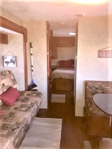 RV rental interior: A practical layout with a patterned sofa, dining booth, and a private bedroom at the back.. Forest River Wildwood 2010
