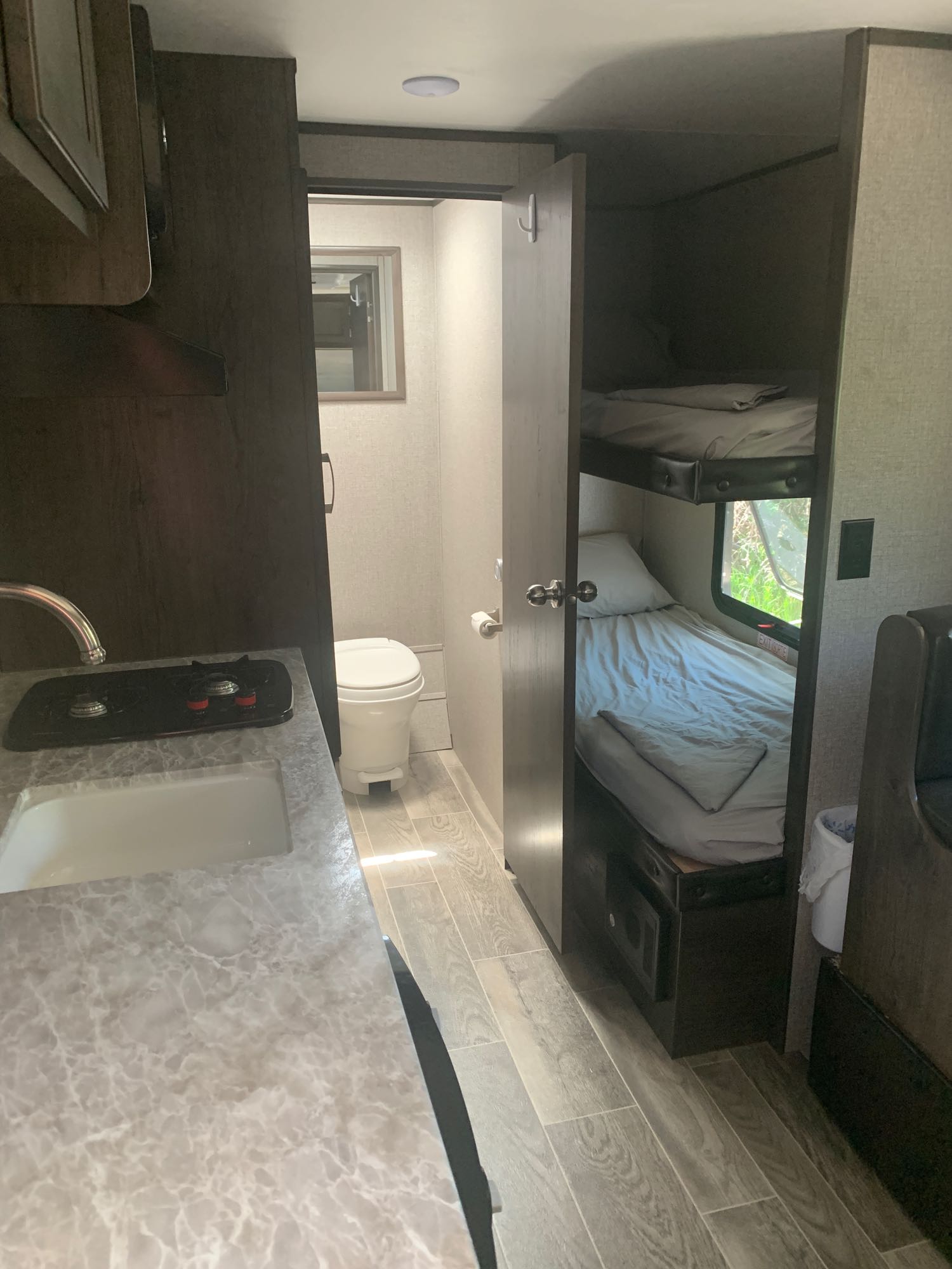 Explore this RV rental's interior: functional kitchen, compact bathroom with toilet, and cozy bunk beds for comfortable travel.. Jayco Jay Flight 2021