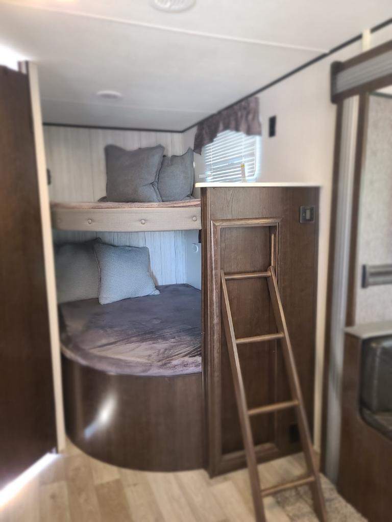 Inside an RV rental: two cozy bunk beds with pillows and a ladder provide comfortable sleeping for travel adventures.. Heartland Pioneer 2021
