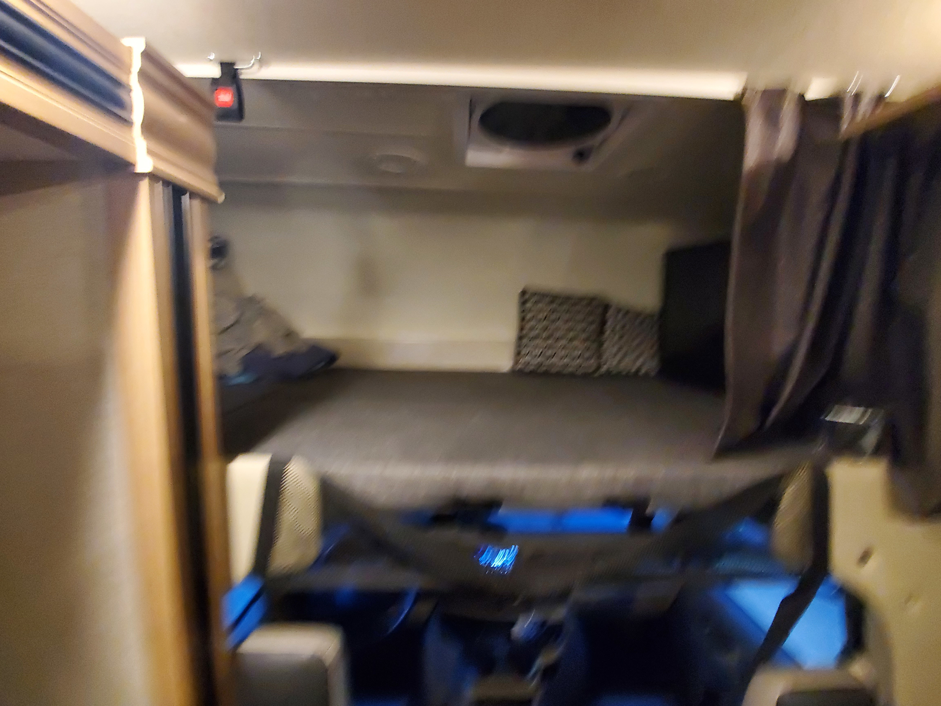 Cozy RV rental interior showcasing an overhead bunk bed and the driver's cabin below for comfortable travel.. Thor Motor Coach Outlaw 2021