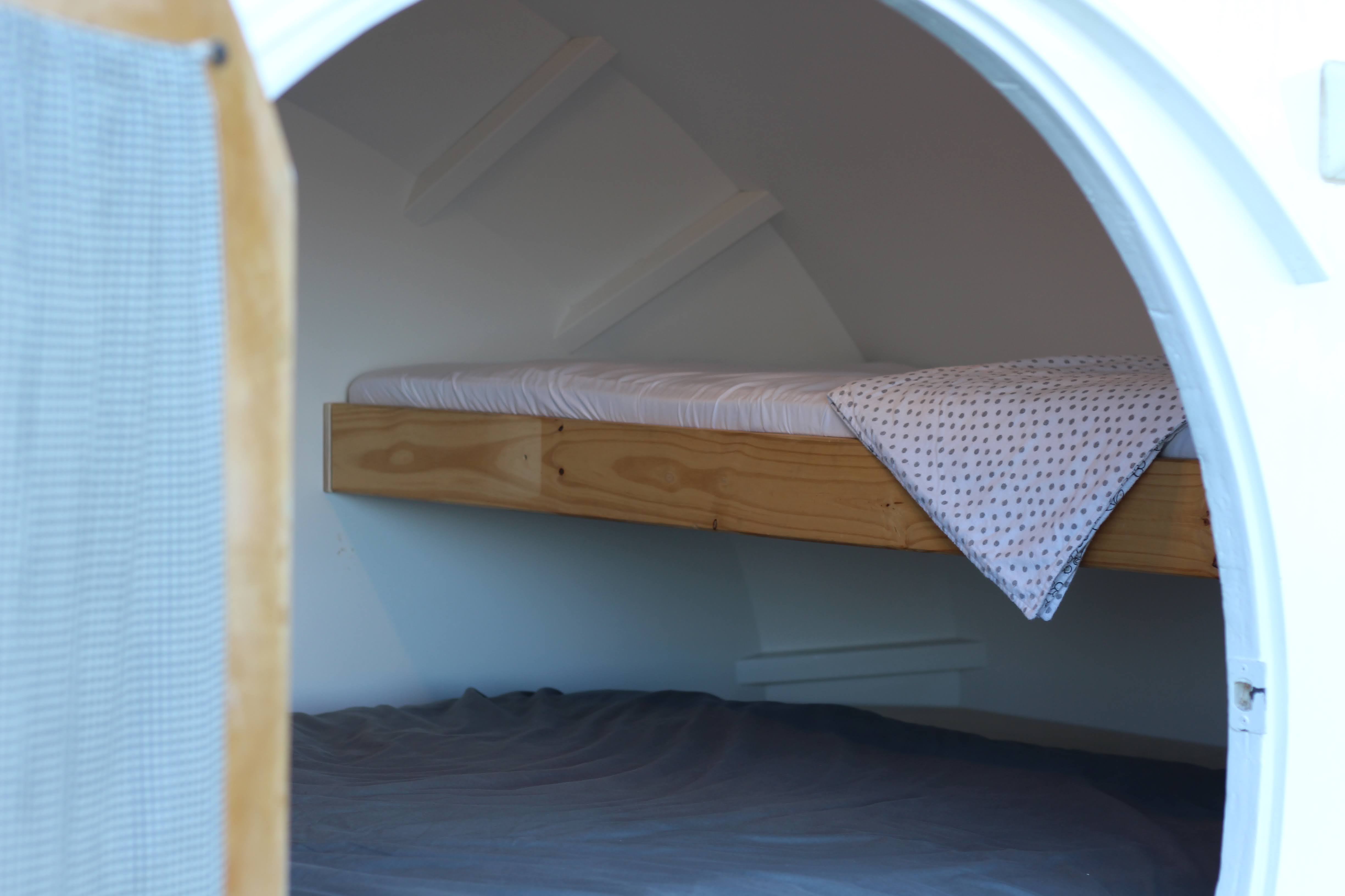 Cozy rv rental interior featuring bunk beds: top with polka dot blanket, bottom with grey bedding in a compact space.. Custom Teardrop 2019