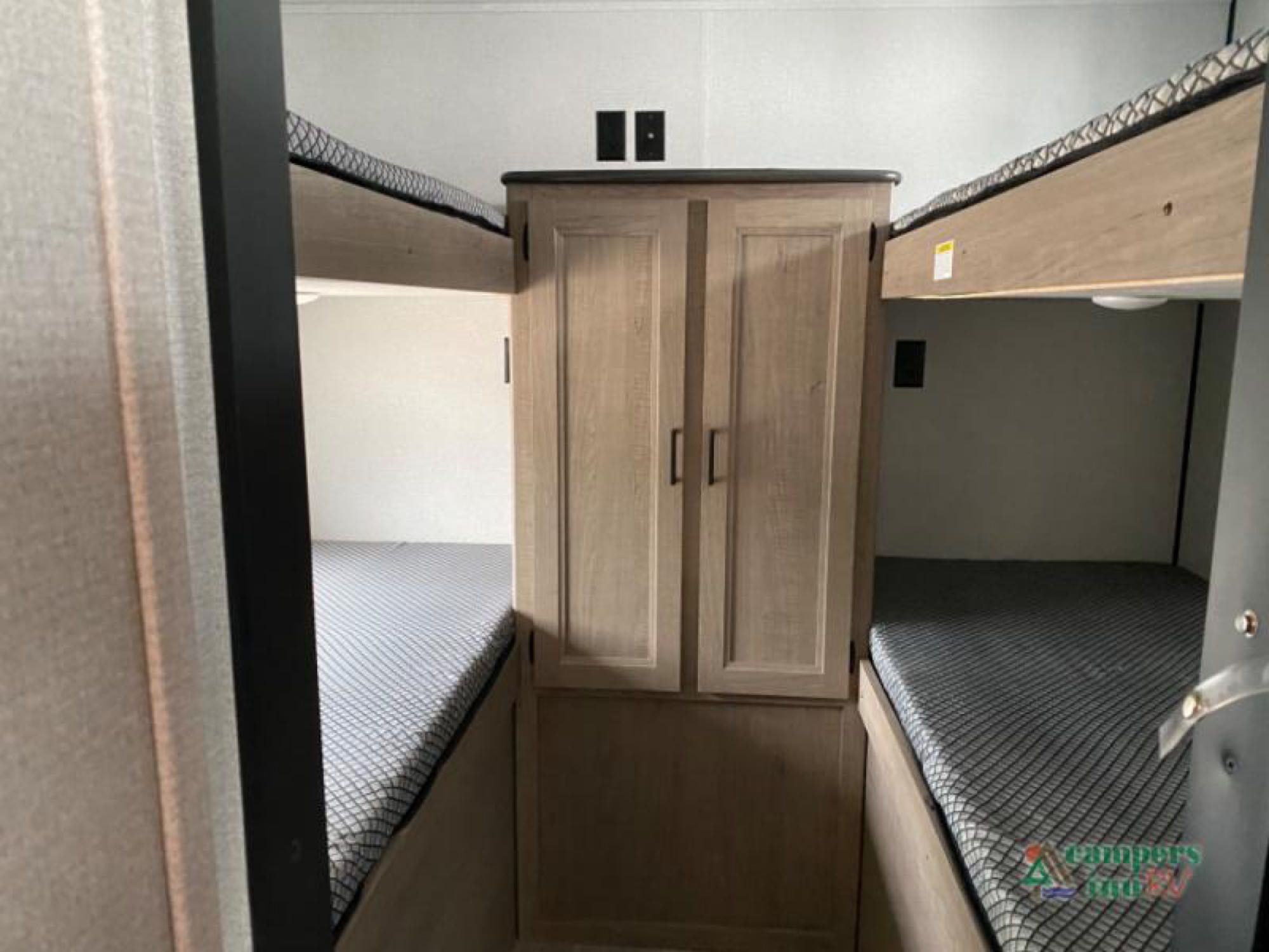 RV rental's bunk bed area featuring two sets of bunks with mattresses and a central storage cabinet.. Keystone Hideout 2021