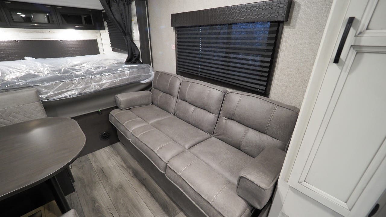 This RV rental's interior offers a grey sofa, bed, and dining table for your comfortable travels.. Jayco Jay Feather 2021