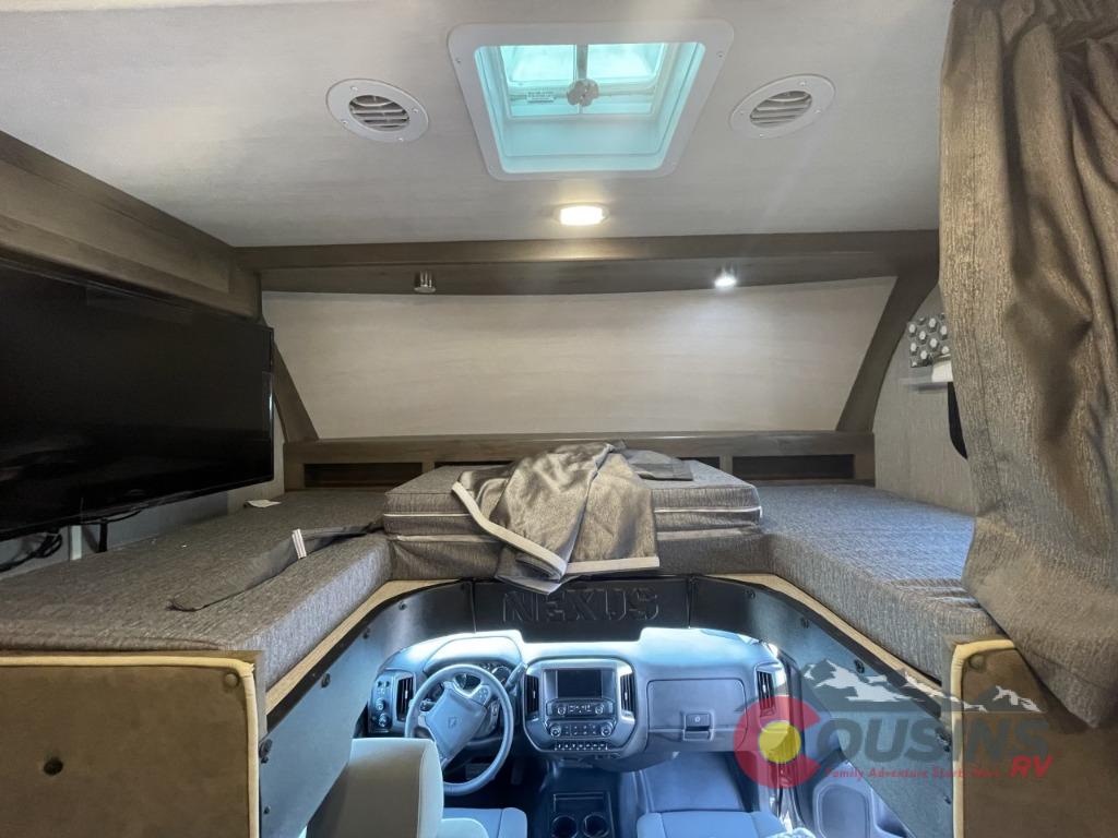 RV rental interior: spacious over-cab bunk bed with TV, skylight, and driver's area view.. Nexus Rebel 2022