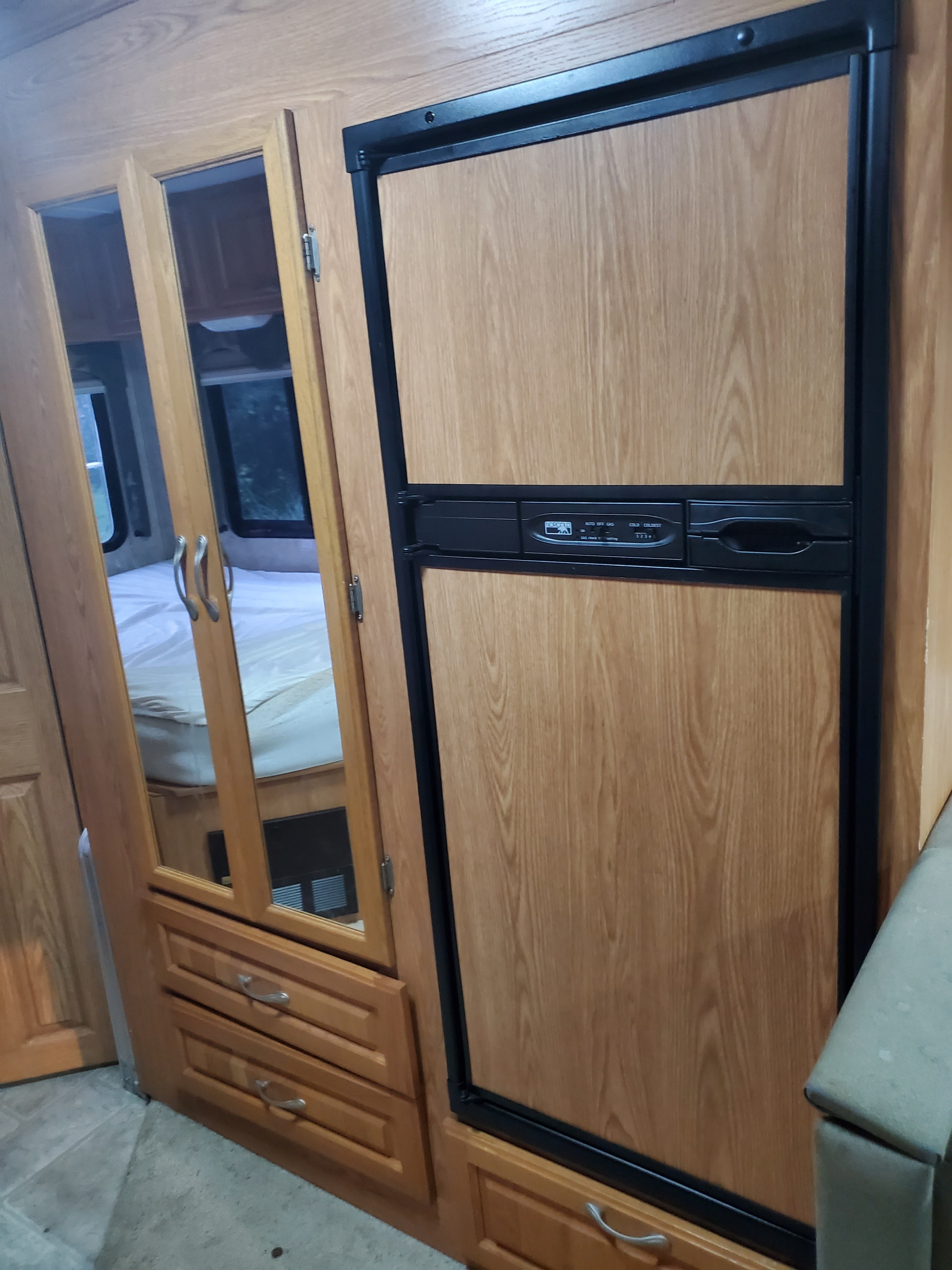 **RV rental** interior: a built-in refrigerator and mirrored wardrobe doors reflecting a bed, showcasing compact living.. Thor Motor Coach Four Winds 2004