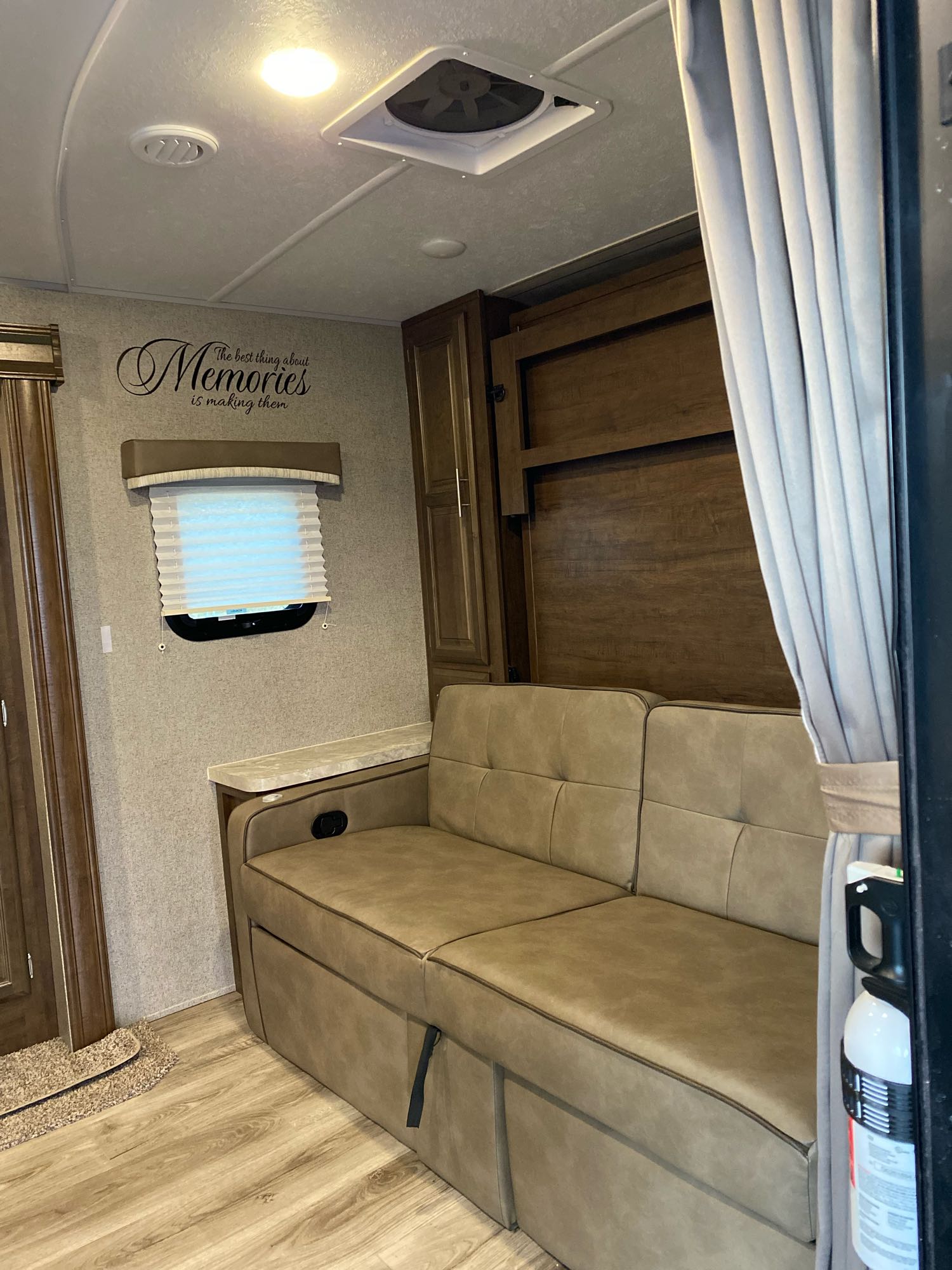Inside an RV rental: a tan sofa, window with blinds, wood paneling, and an inspiring "Memories" wall decal.. Flagstaff Micro Lite 2021