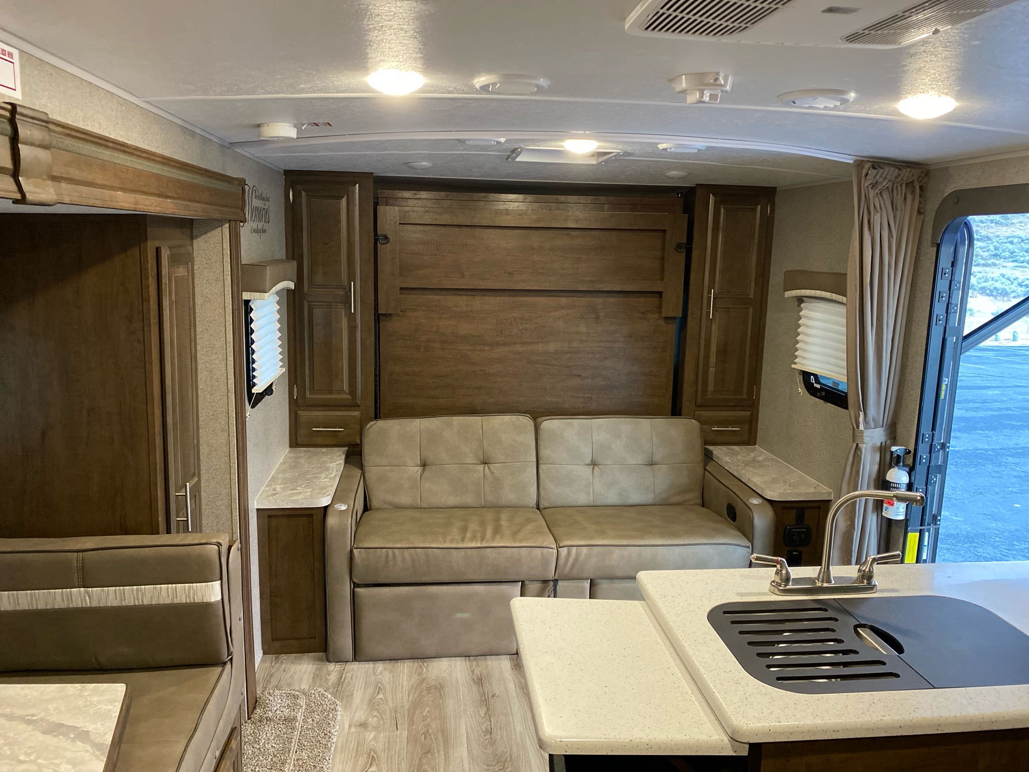 Modern RV rental interior showing a compact kitchen, convertible sofa, and dinette, offering versatile living space.. Flagstaff Micro Lite 2021