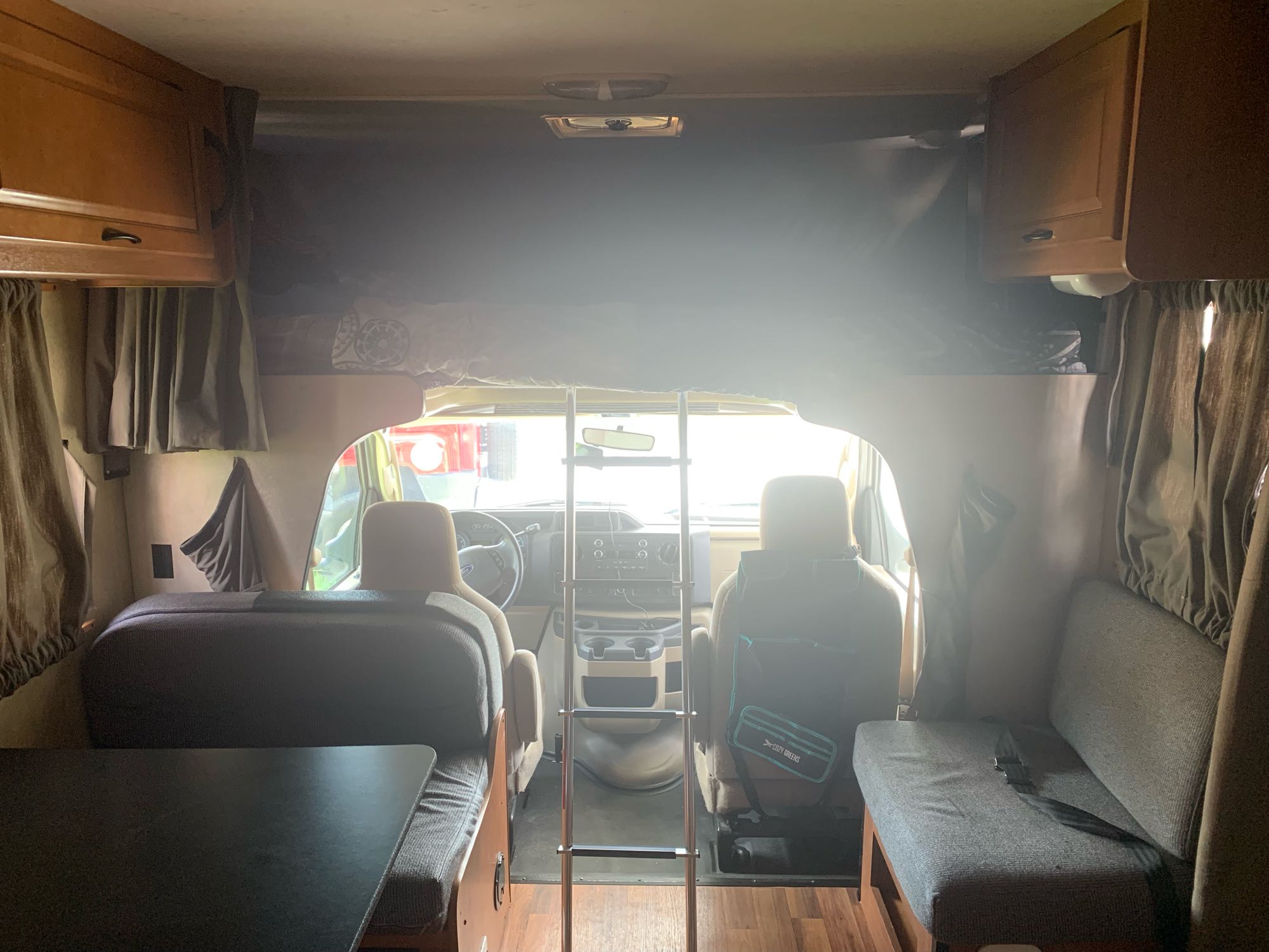 RV rental interior shows overhead bunk with ladder, front cab seats, and dinette area, ready for travel.. Thor Motor Coach Four Winds Majestic 2013