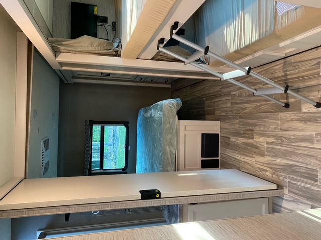 Modern RV rental interior featuring bunk beds with a ladder, wood-look flooring, and a compact, functional living space.. Thor Motor Coach A.C.E 2021