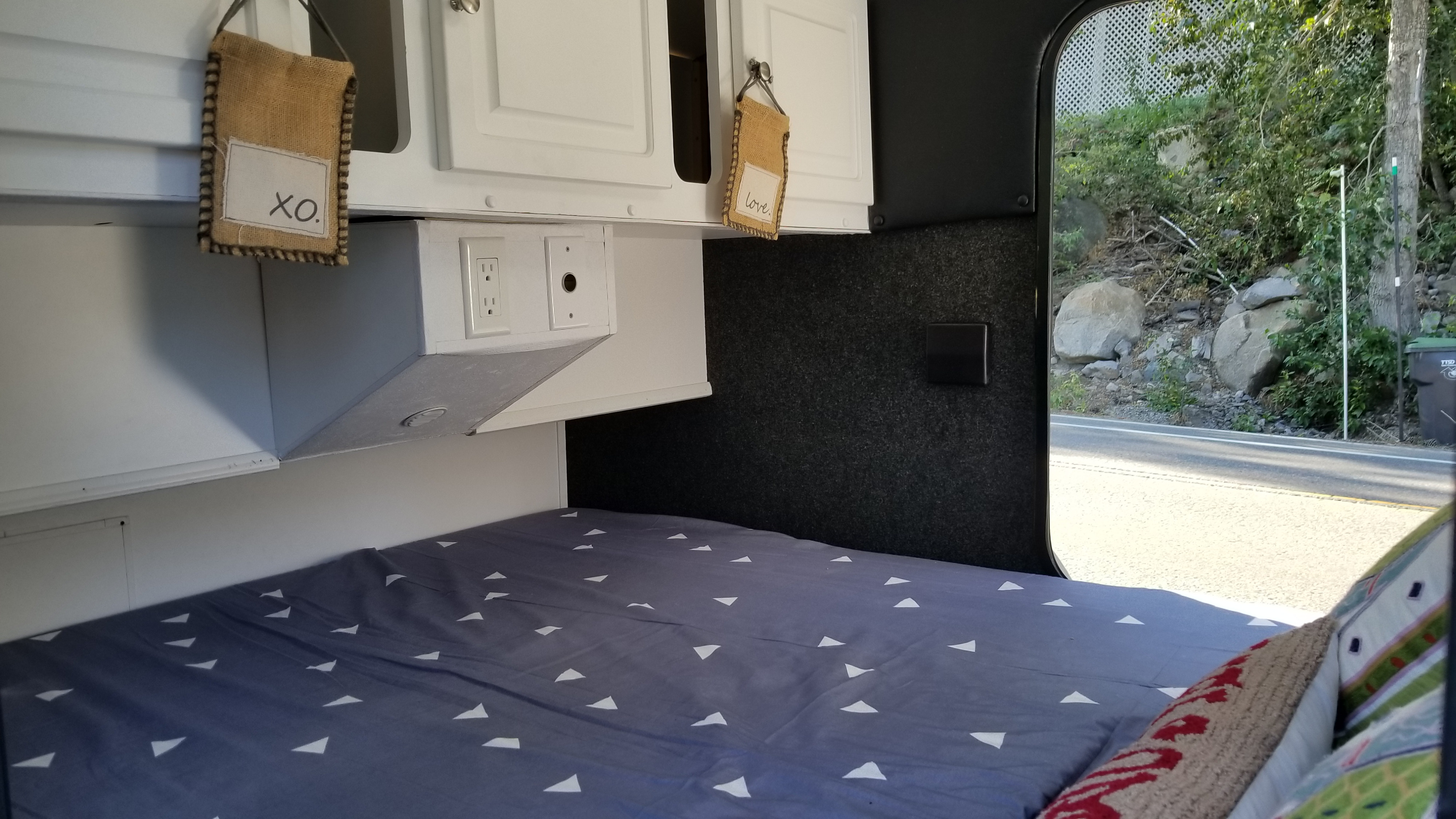 Compact RV rental cabin interior featuring a comfy bed, overhead cabinets, and essential outlets.. Little Guy Other 2011