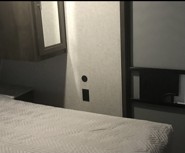 Inside an **rv rental** bedroom, showing a comfy bed with patterned cover, wall cabinet, and sliding door. Ideal for travelers.. Coleman 285BH 2021