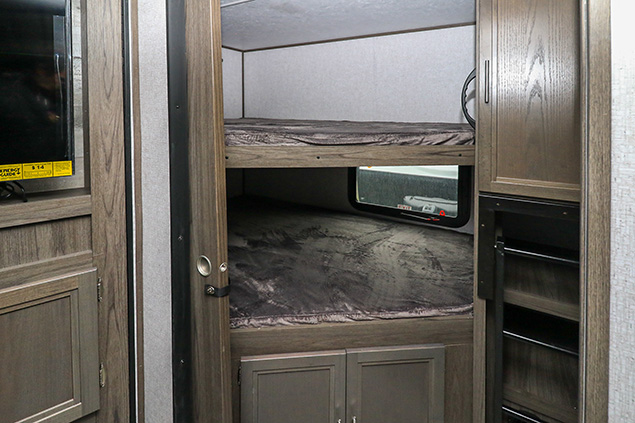 Inside an RV rental: cozy bunk beds, a TV, storage, and a ladder, perfect for families.. Dutchmen Kodiak 2021