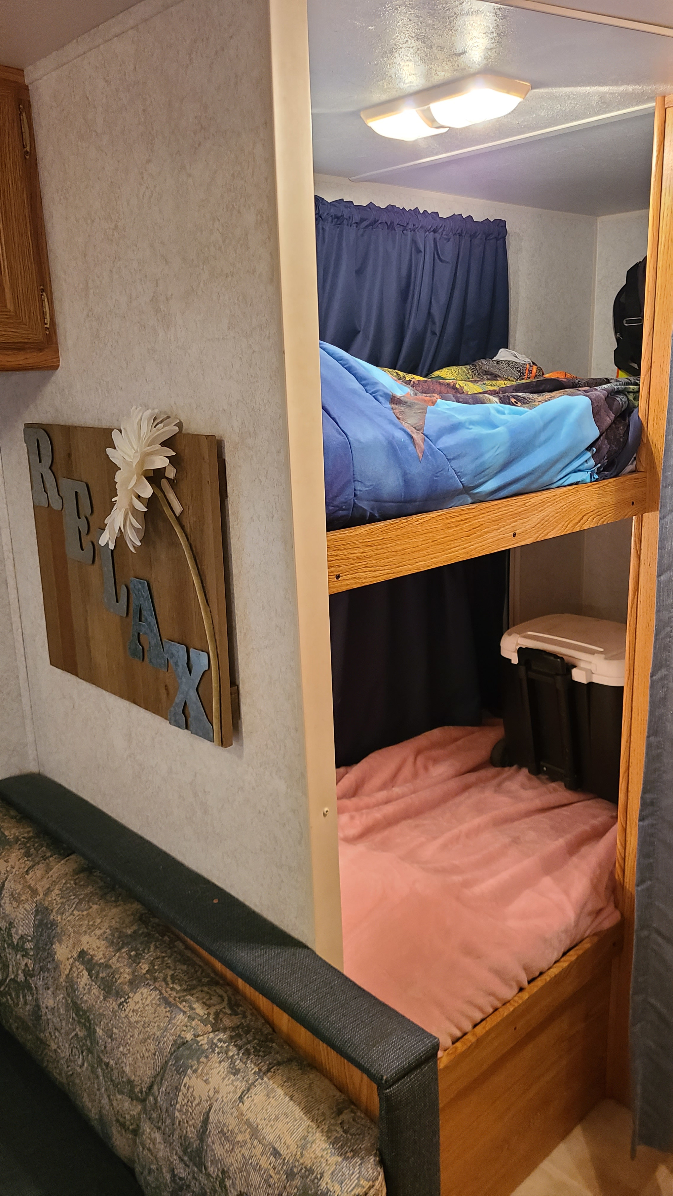 Cozy RV rental interior featuring comfortable bunk beds, a patterned couch, and "RELAX" wall decor, perfect for family adventures.. Dutchmen Four Winds Lite BH29 2003