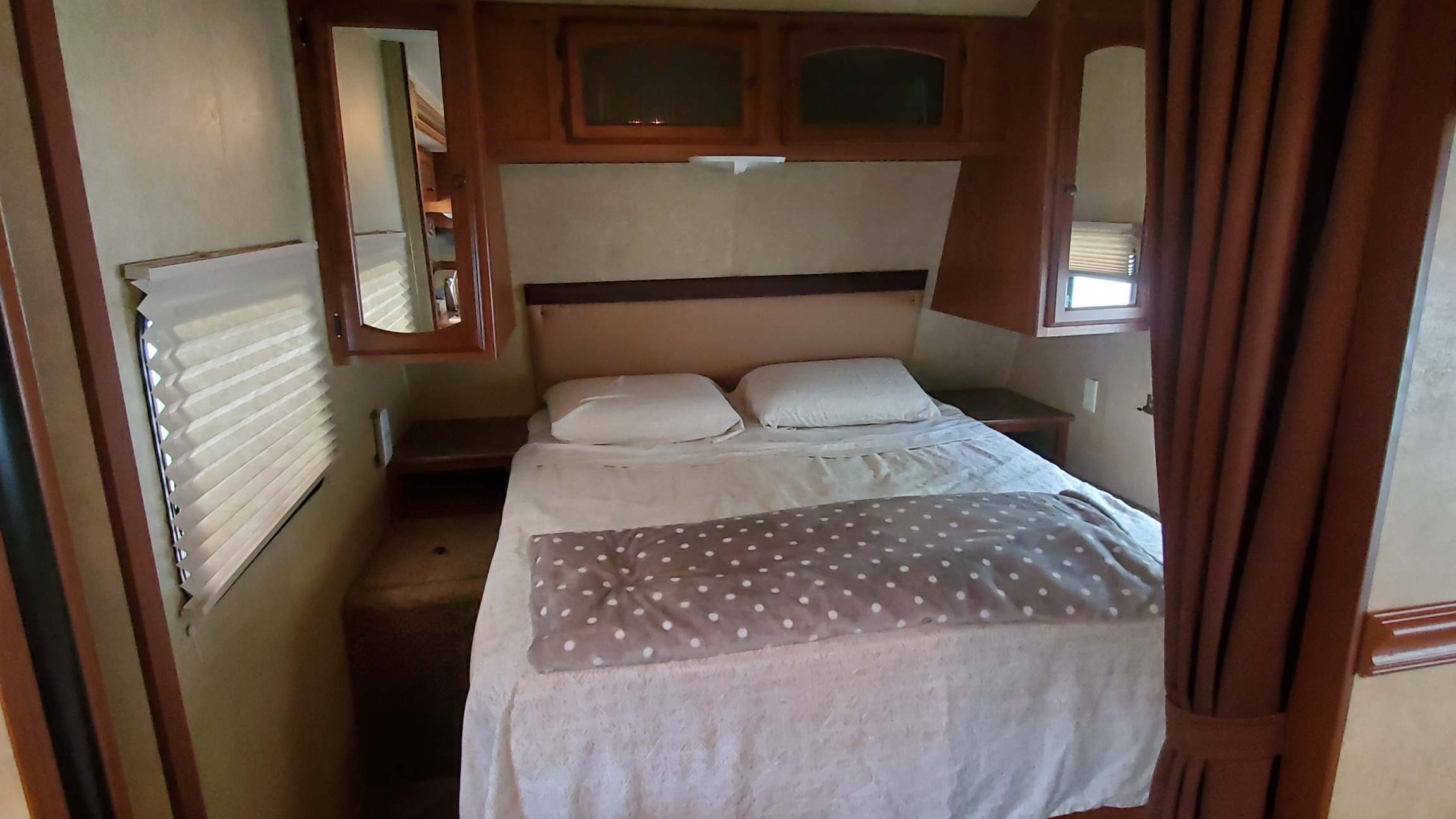 Inside an RV rental: a compact bedroom featuring a comfortable bed, overhead cabinets, and window blinds.. Dutchmen Dutchmen 2012