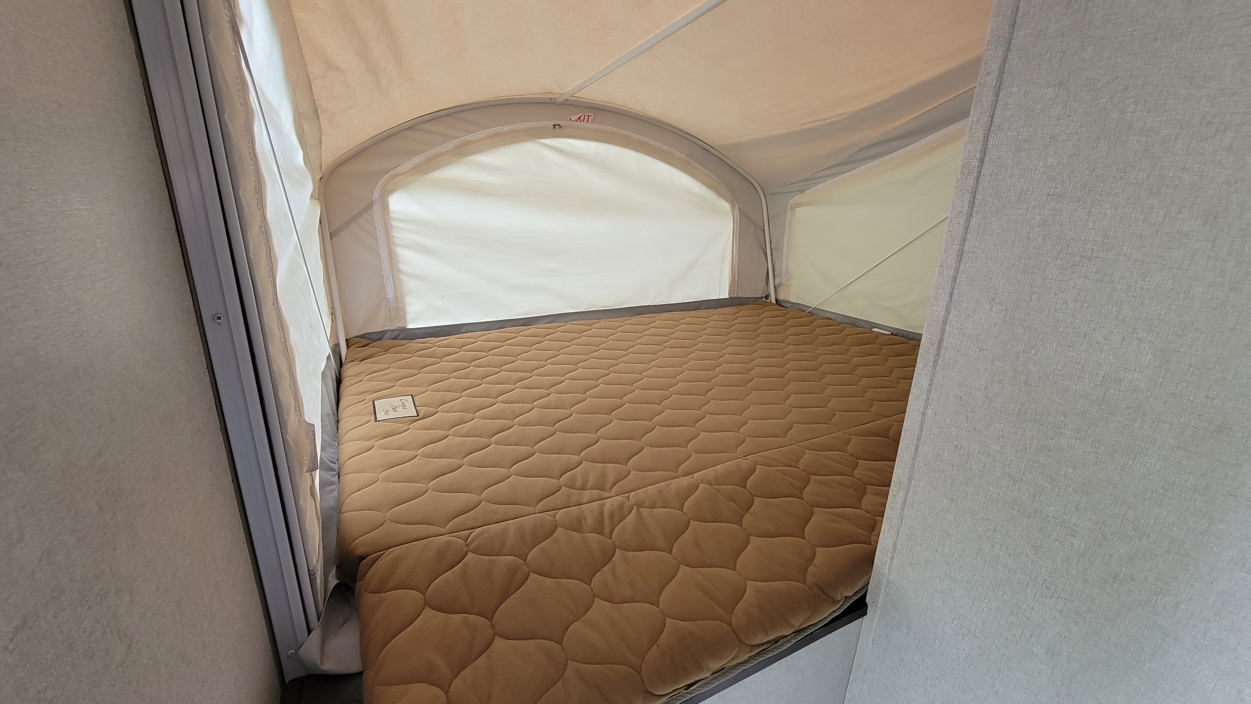 RV rental's cozy pop-out bed, featuring a brown quilted mattress, offers a comfortable sleeping space.. Forest River 16RB 2019