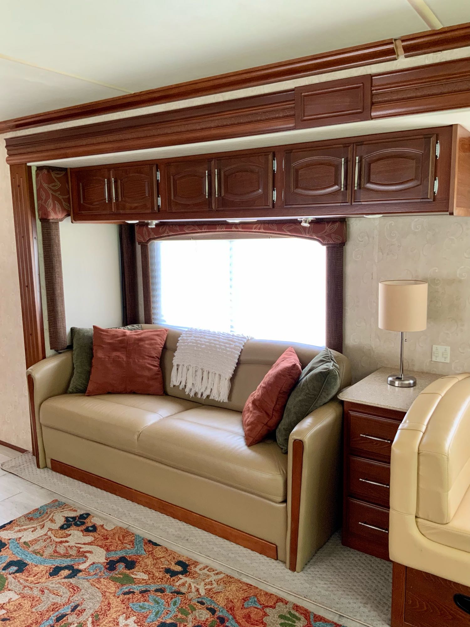 Cozy RV rental living space with a pull-out sofa, ample storage, and warm decor, perfect for travel.. Fleetwood Excursion 2008