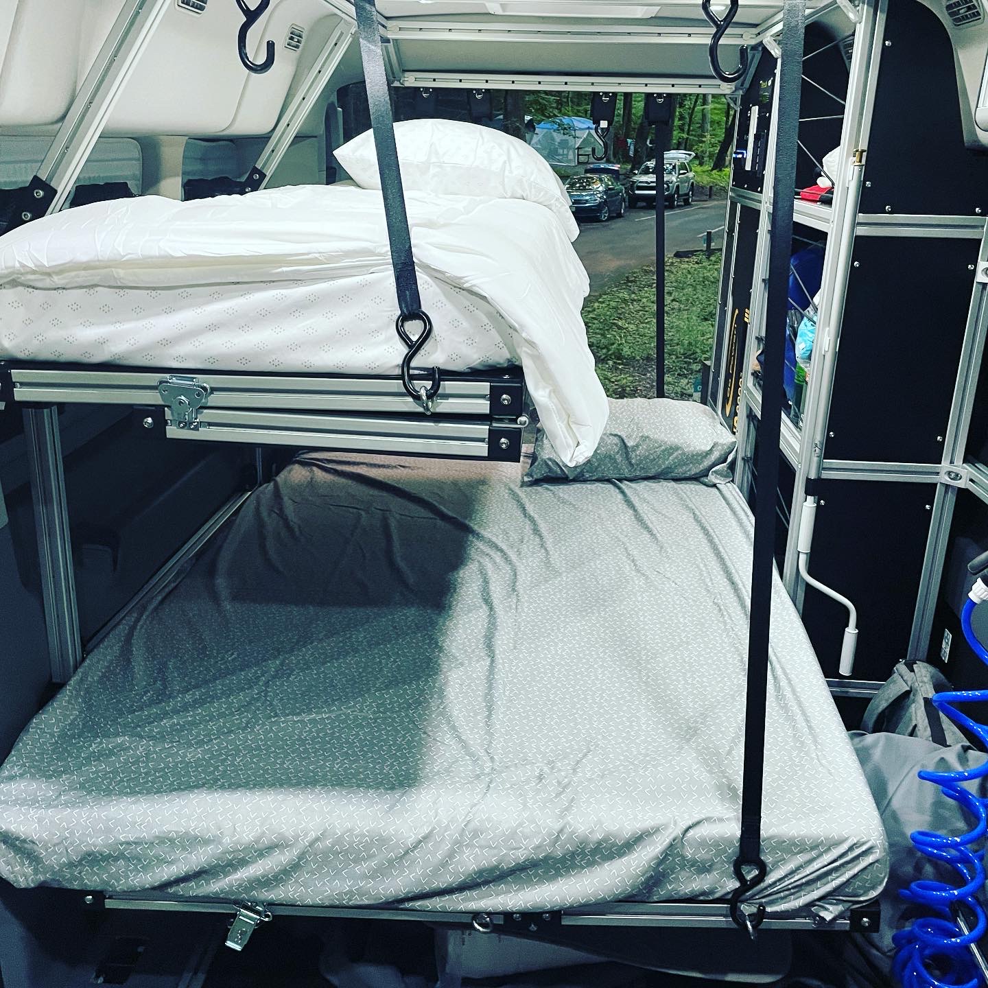 See a camper van RV rental interior with suspended white bunk beds over a grey bed, ideal for camping adventures.. Ford transit 2017