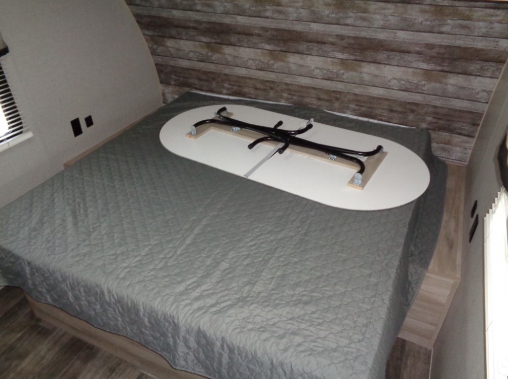 RV rental bedroom with a bed & multi-functional table stowed upside down. Smart space-saving design for a camper.. Coachmen Catalina 2021