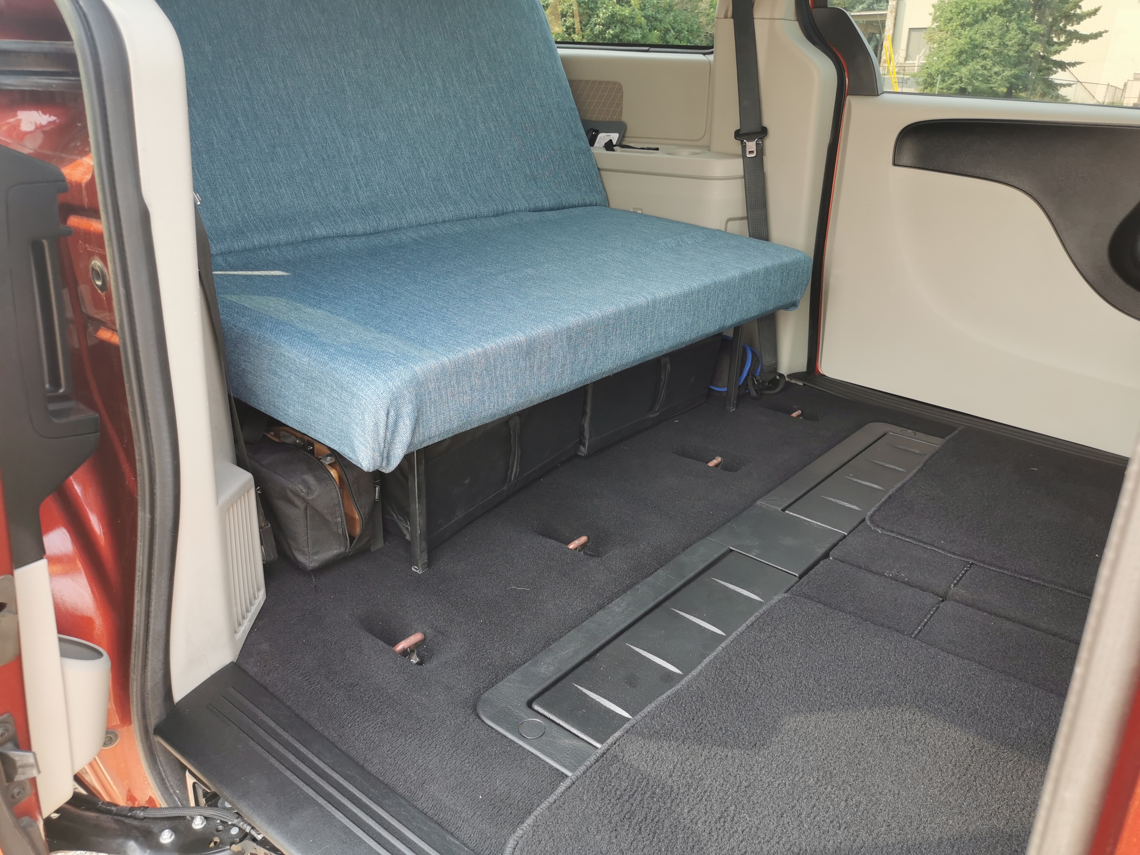 Inside a spacious camper van setup, a blue bench seat provides comfortable seating and storage, perfect for an rv rental trip.. Dodge Other 2012