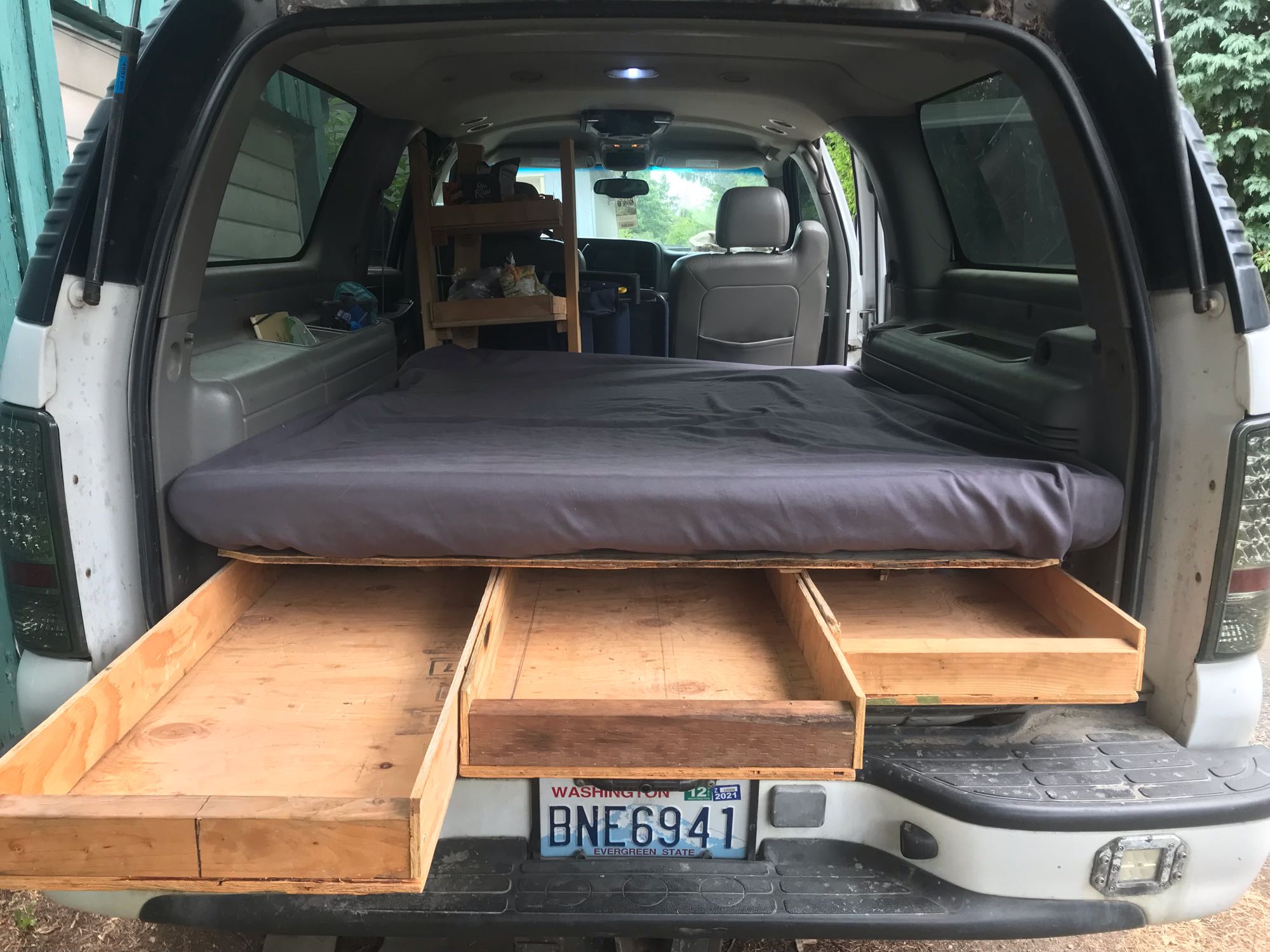 Rear view of a DIY SUV camper. Features a bed platform & pull-out storage drawers for your next rv rental adventure.. Gmc Yukon XL 2002
