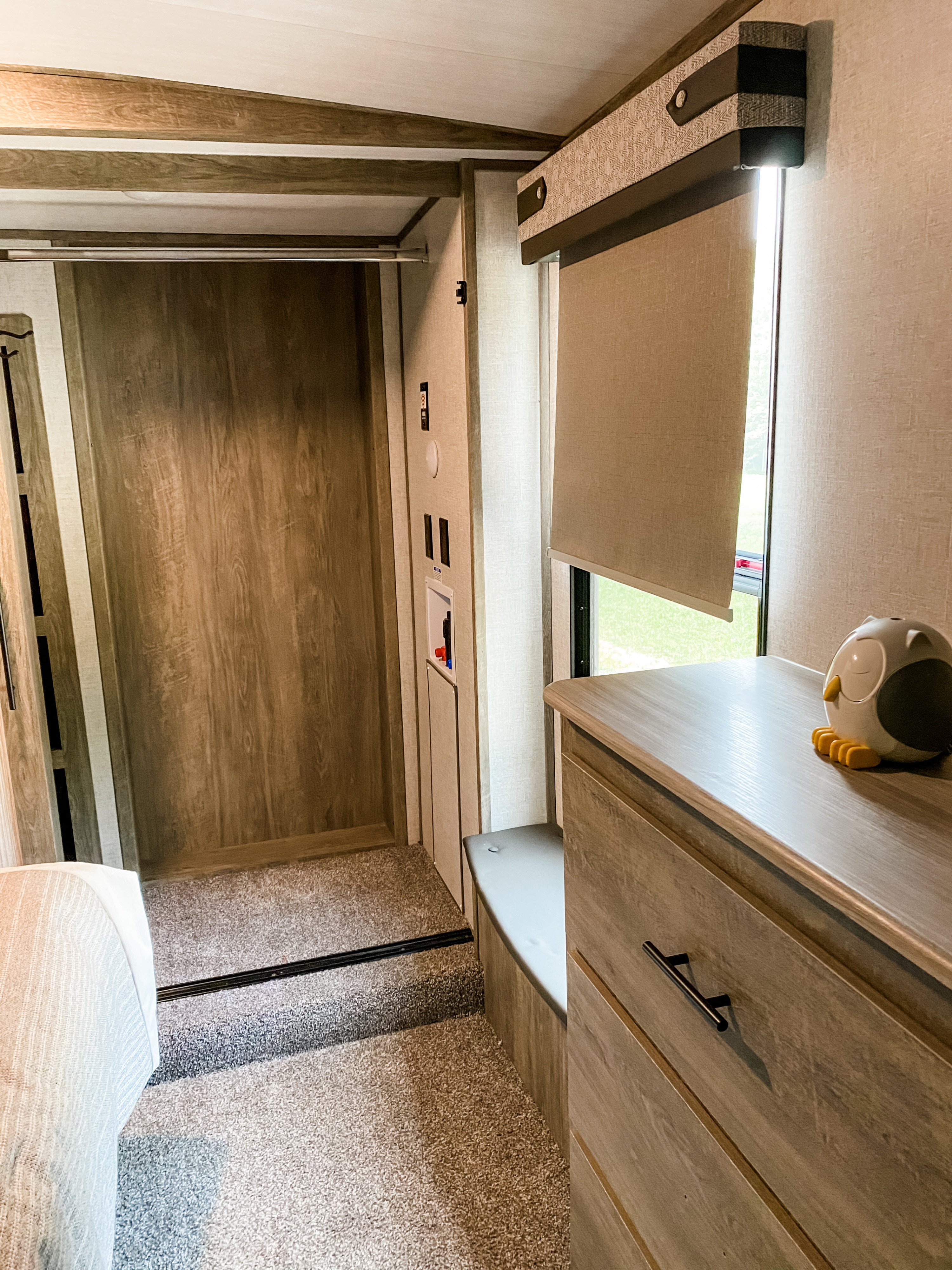 Cozy RV rental interior showing a bedroom with wood-grain finishes, a dresser, utility hookups, and a window with blinds.. Forest River Other 2021