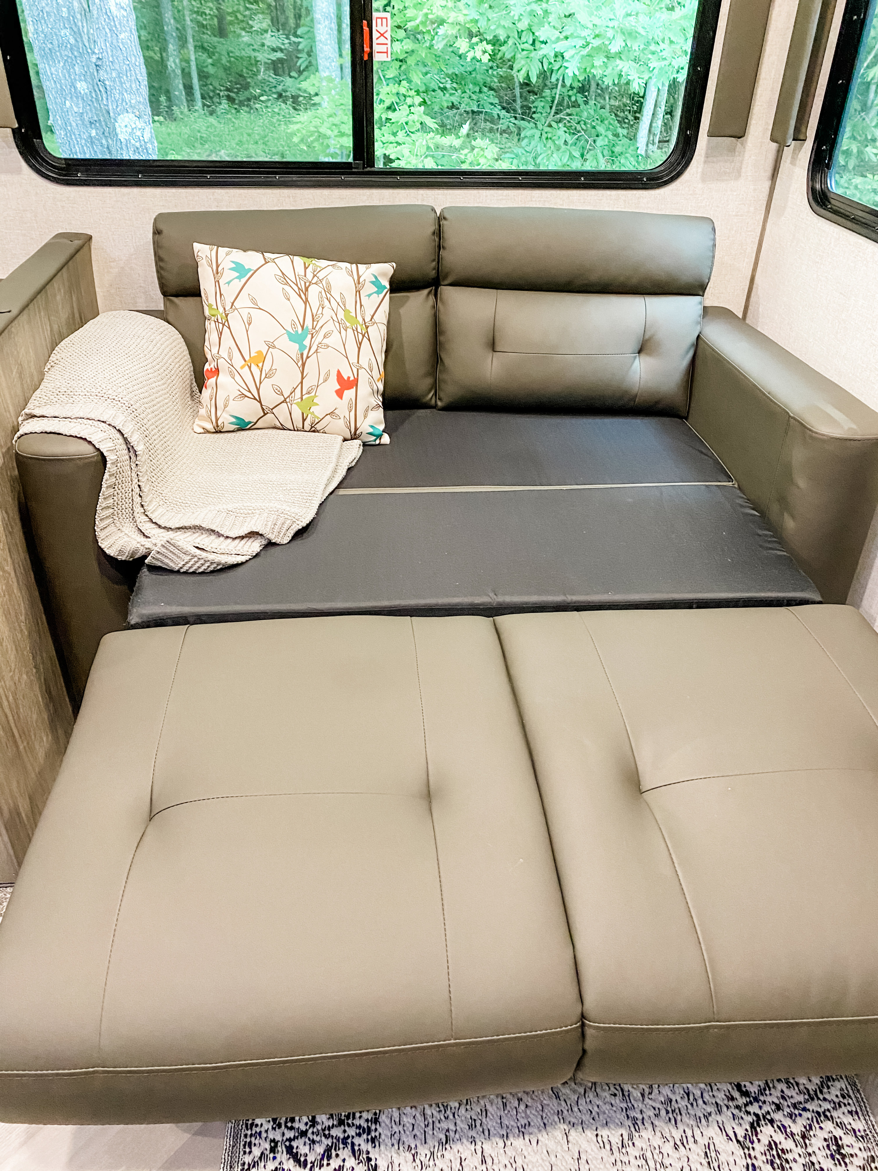 Cozy RV sofa-bed, partially converted, with a decorative pillow and a forest view, perfect for an rv rental.. Forest River Other 2021