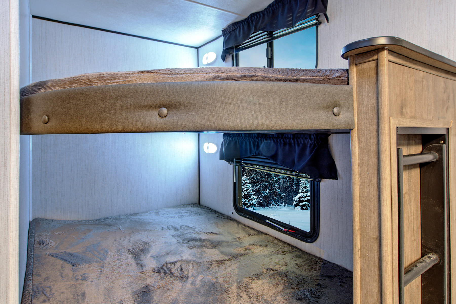 Cozy bunk beds in an RV rental, offering scenic window views of sky and snowy forest. Ideal for trips.. Heartland RVs Pioneer 2021