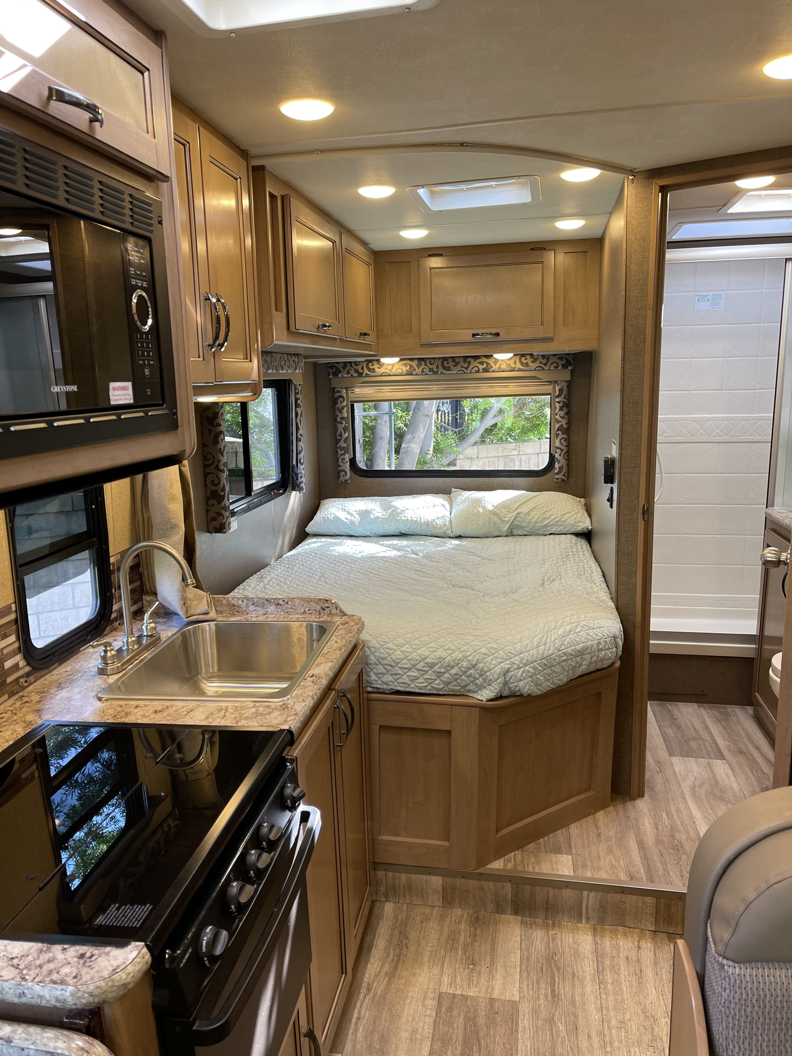 Cozy RV rental interior showcasing a compact kitchen, comfortable bedroom, and accessible shower for a great travel experience.. Thor Four Winds 2019