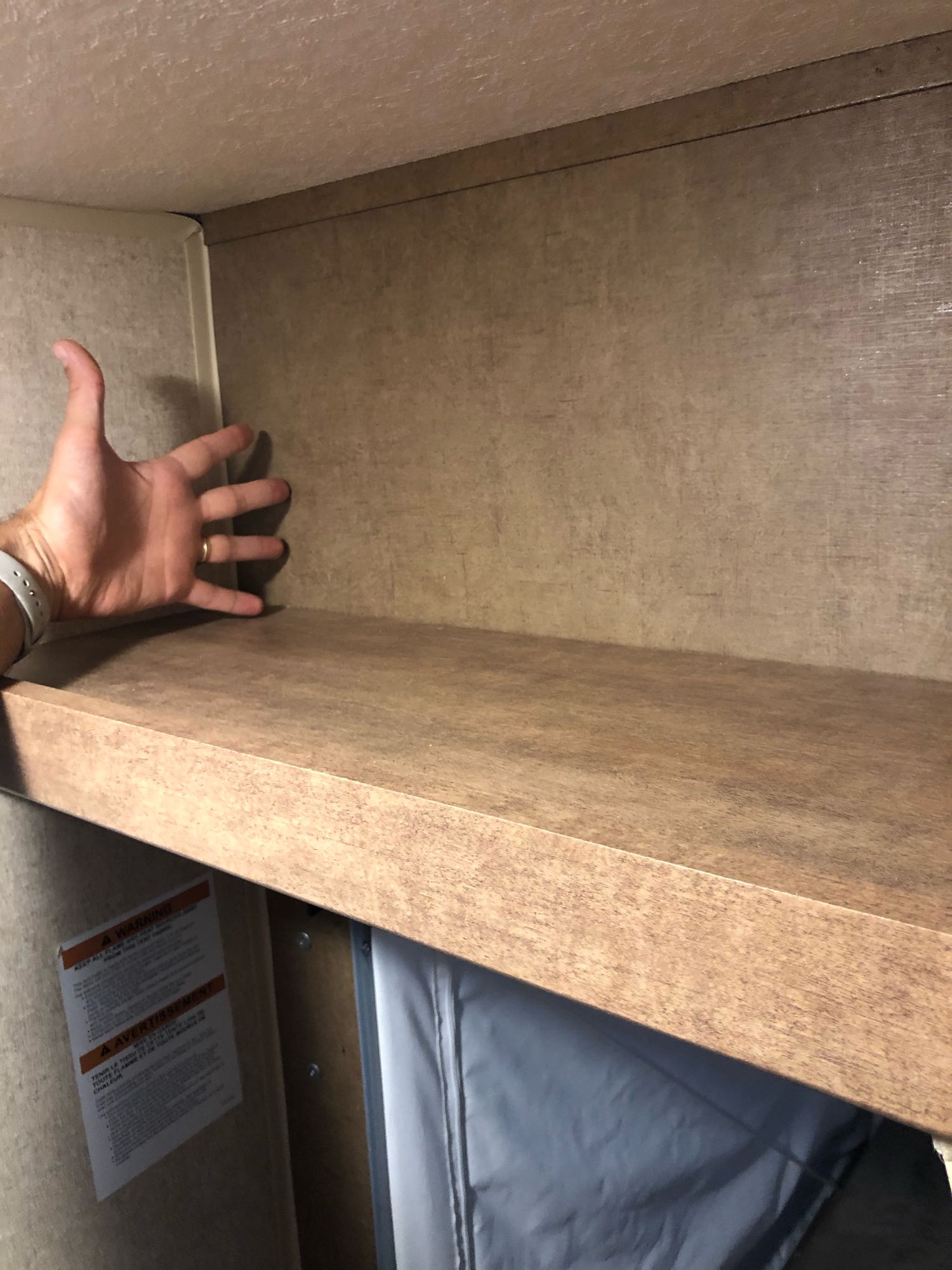 Bunk shelf in an RV rental with a hand showing its depth, highlighting compact interior storage.. Starcraft Launch 2018