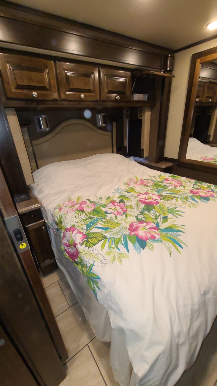 Cozy RV rental bedroom featuring a floral duvet, wood cabinets, and comfortable bed.. Allegro Allegro Motorhome 2016