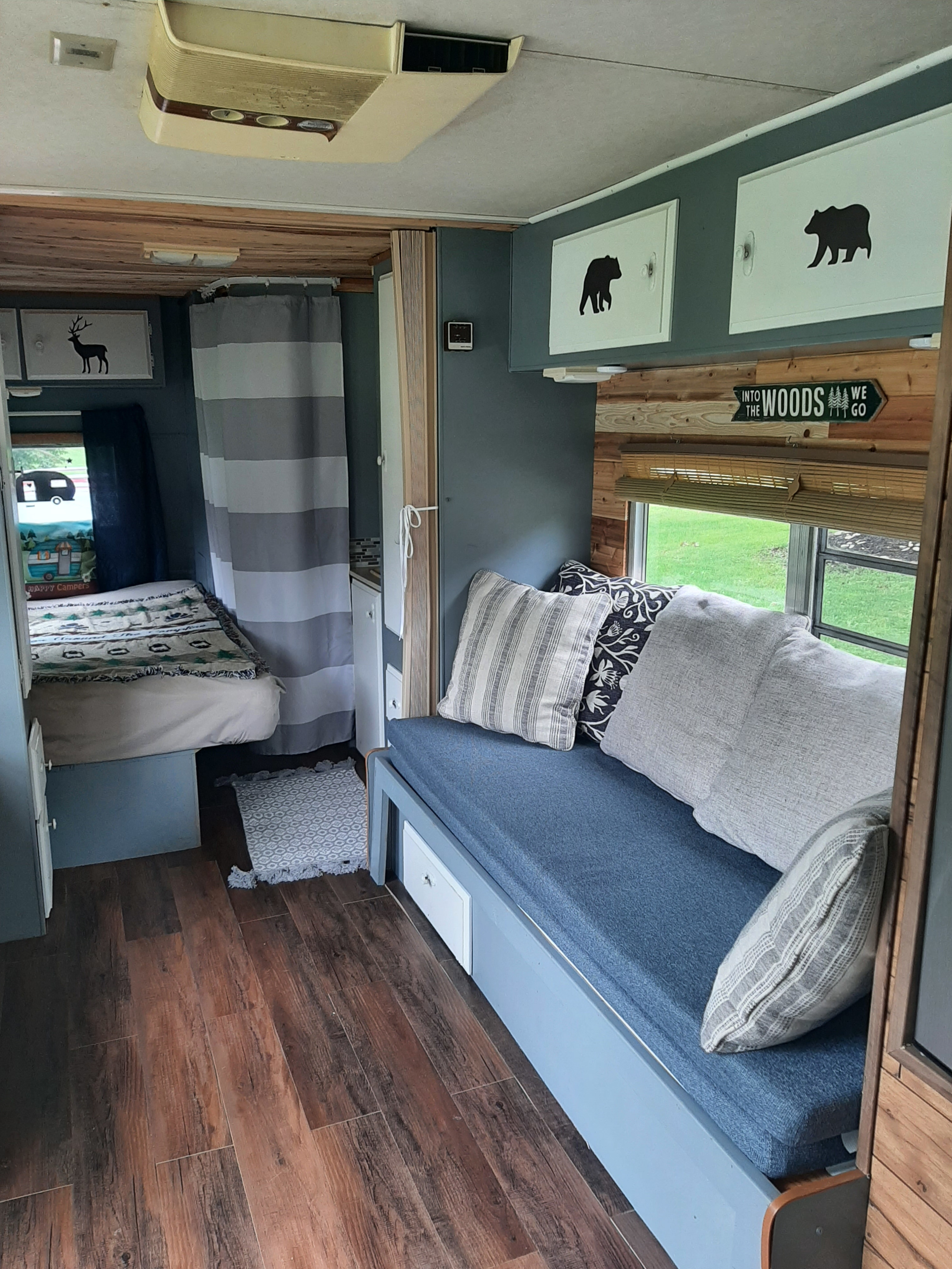 Rustic RV rental interior with a blue couch, bed, and charming woodsy decor, perfect for adventurous travel.. Fleetwood Wilderness 1990