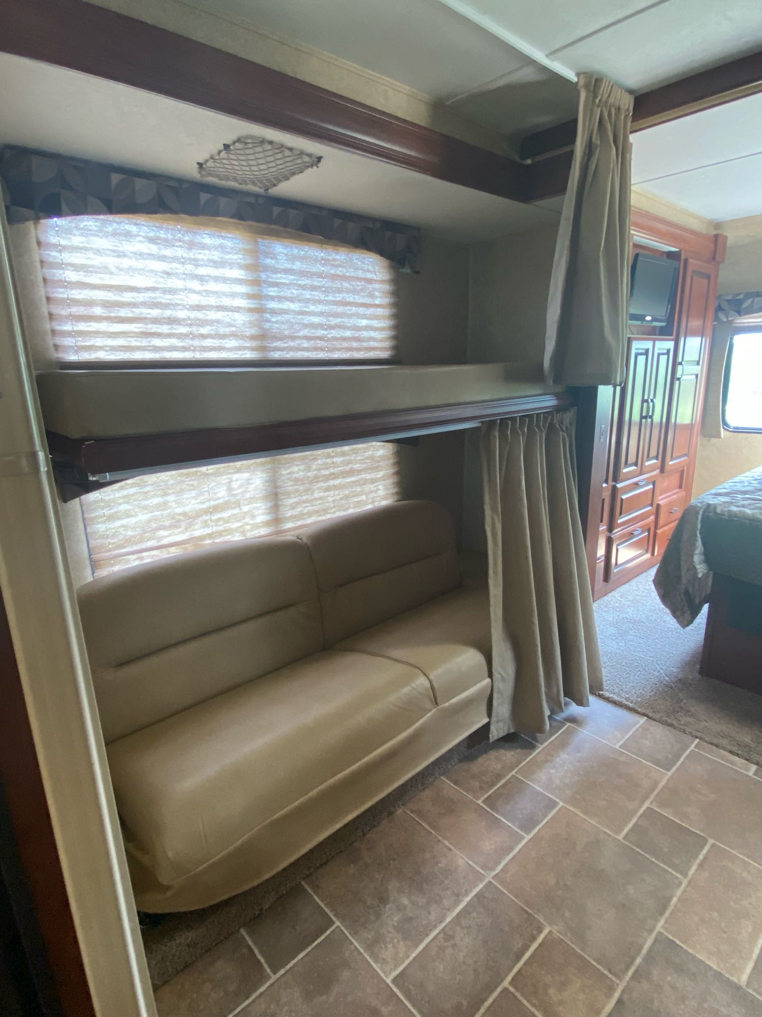 RV rental interior featuring bunk beds, a comfortable sofa, and privacy curtains, leading to the main bedroom area.. Forest River Ford Sunseeker 2013