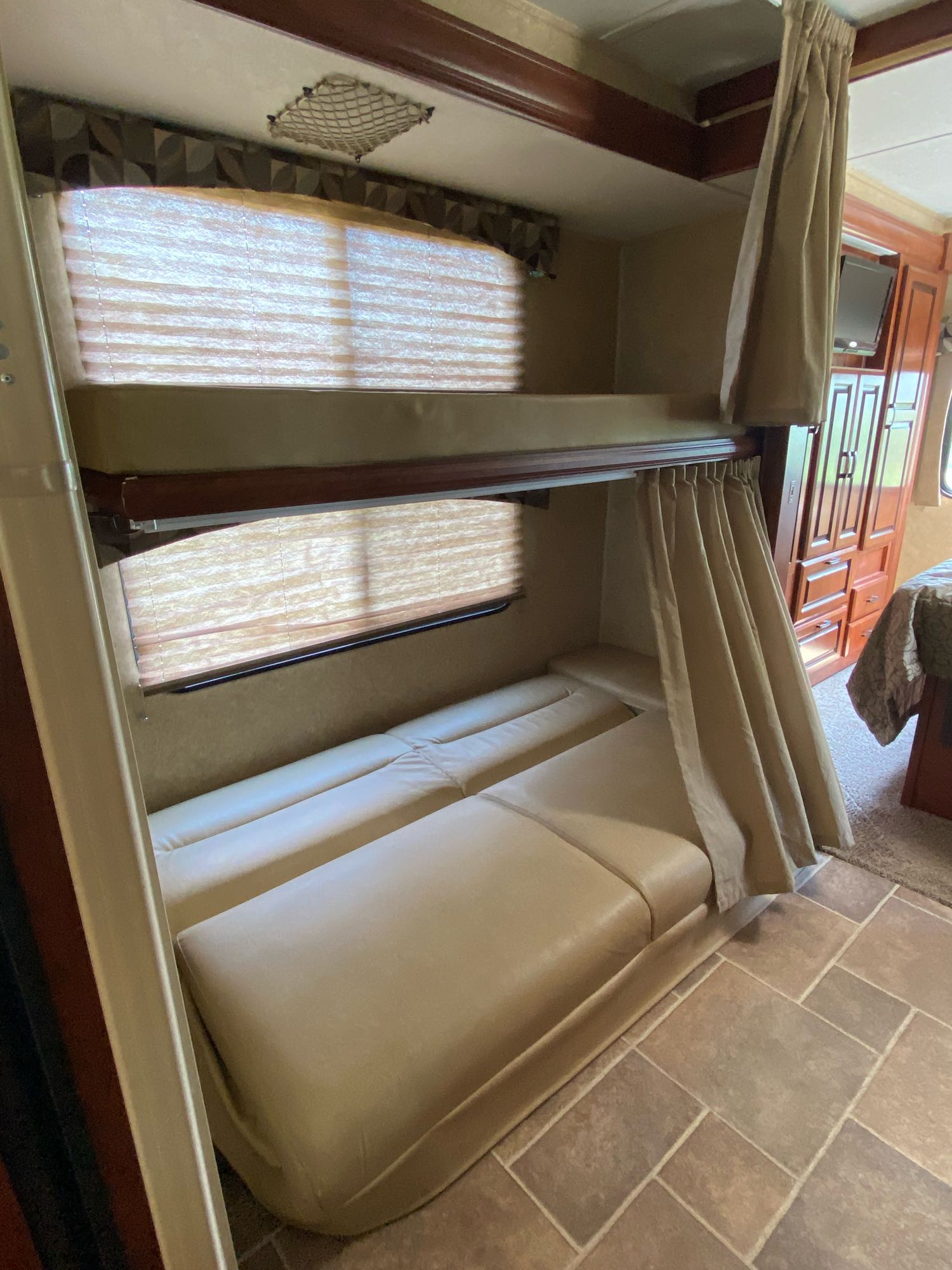 Inside an RV rental: bunk beds with light mattresses, windows, privacy curtains, and top bunk safety net.. Forest River Ford Sunseeker 2013