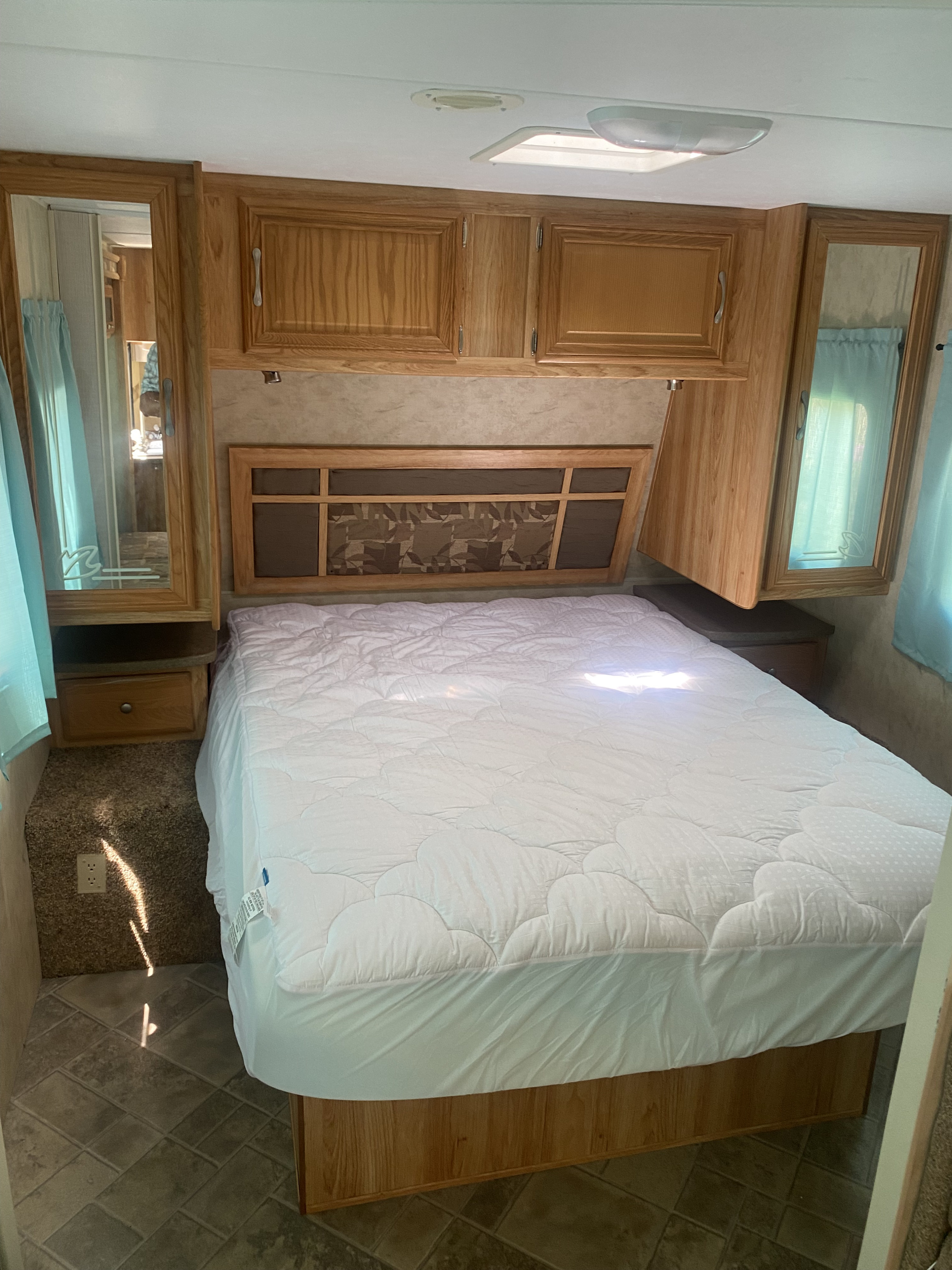 Cozy RV rental bedroom features a white bed, wood cabinetry, mirrored closets, and ceiling lights.. Dutchmen Aerolite 2009