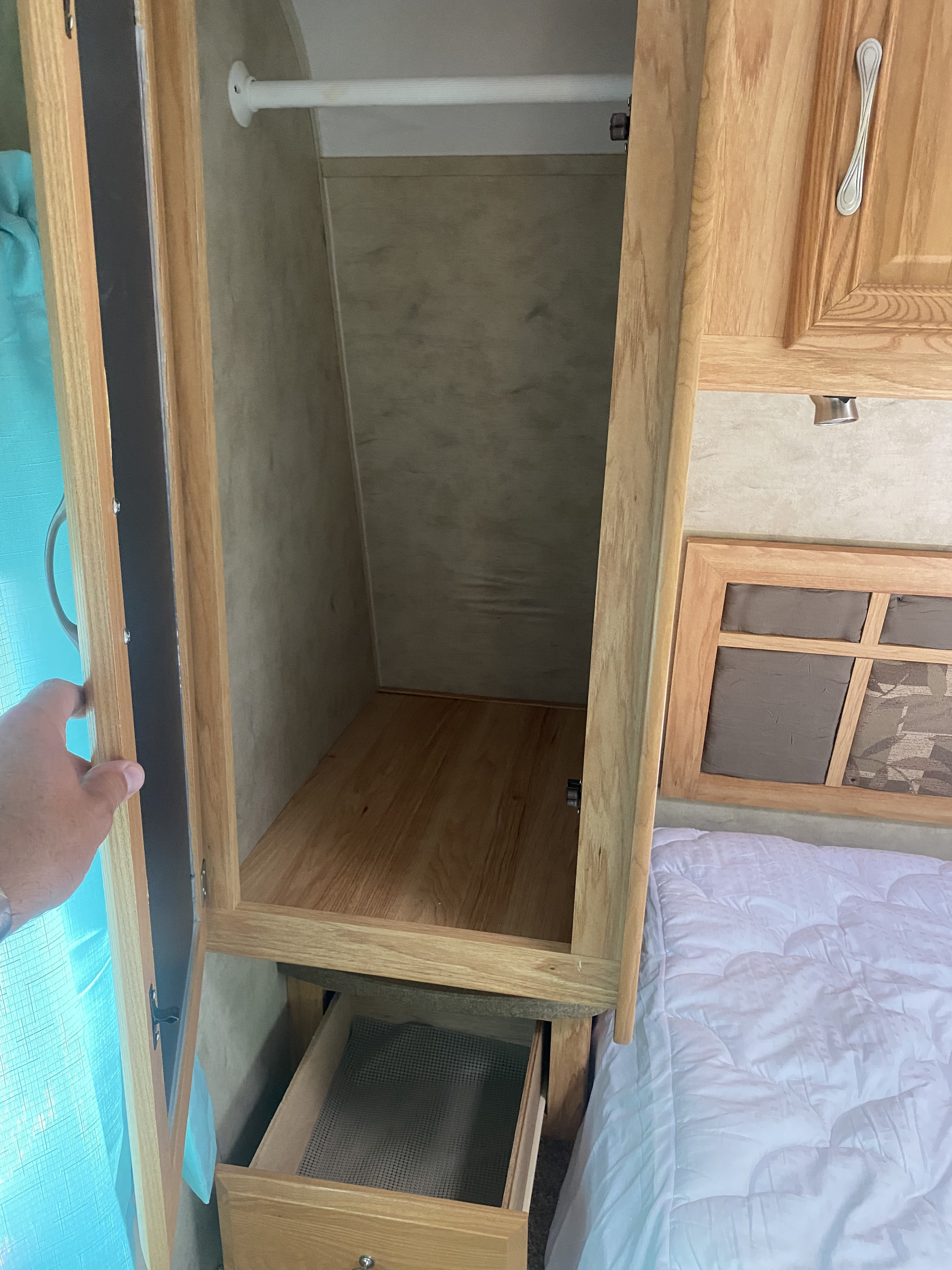 Explore your RV rental! This image shows a compact wardrobe with hanging space, a shelf, and a lower drawer, perfect for your travel needs.. Dutchmen Aerolite 2009