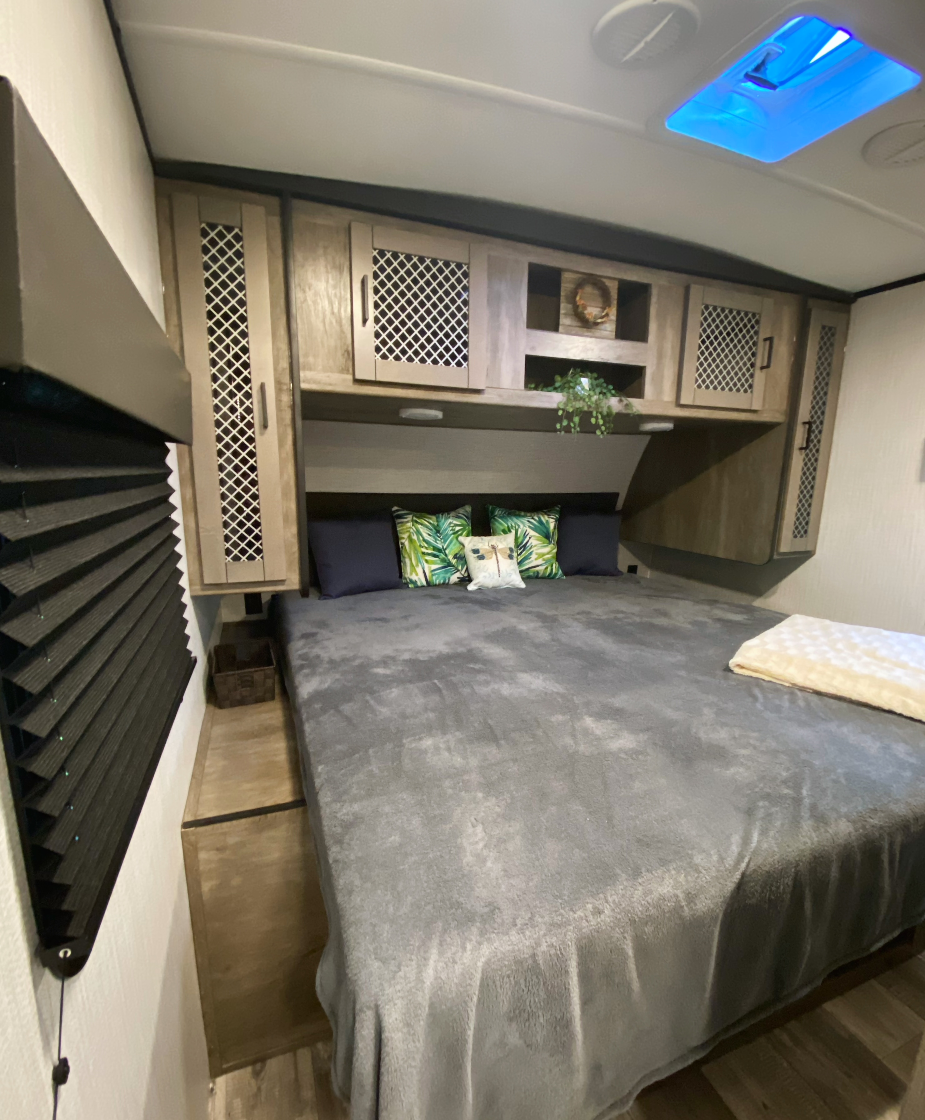Cozy RV rental bedroom with spacious bed, stylish overhead cabinets, and bright blue ceiling light for comfortable travel.. Heartland RVs North Trail 2021