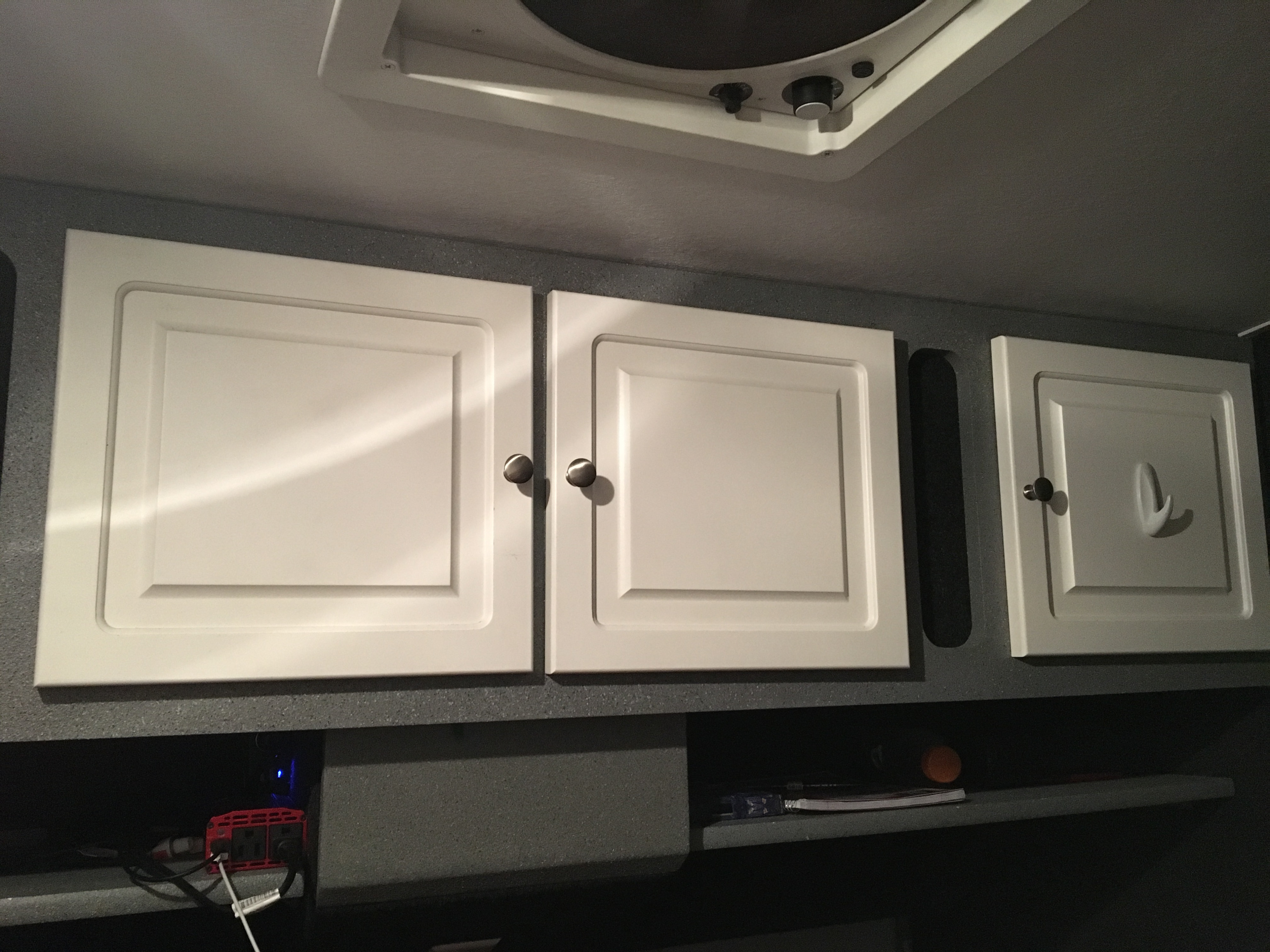 RV rental interior: white overhead cabinets, a ceiling fan, and storage with a power inverter visible.. Little Guy Other 2011
