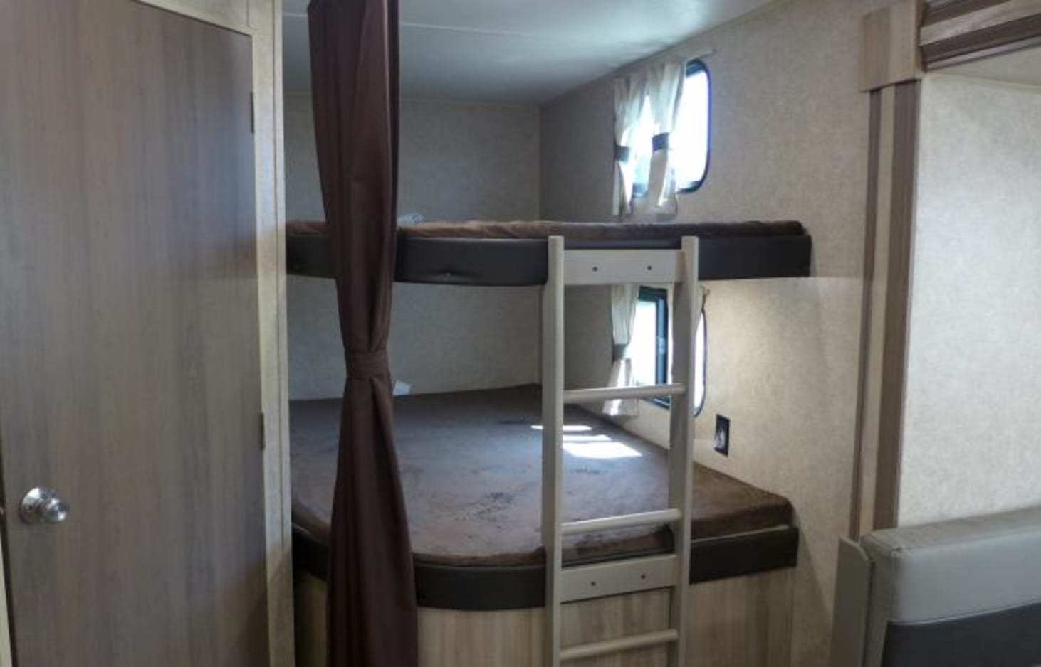 This RV rental interior features practical bunk beds, a ladder, and small windows, offering a compact sleeping space.. Coachmen Catalina 2020