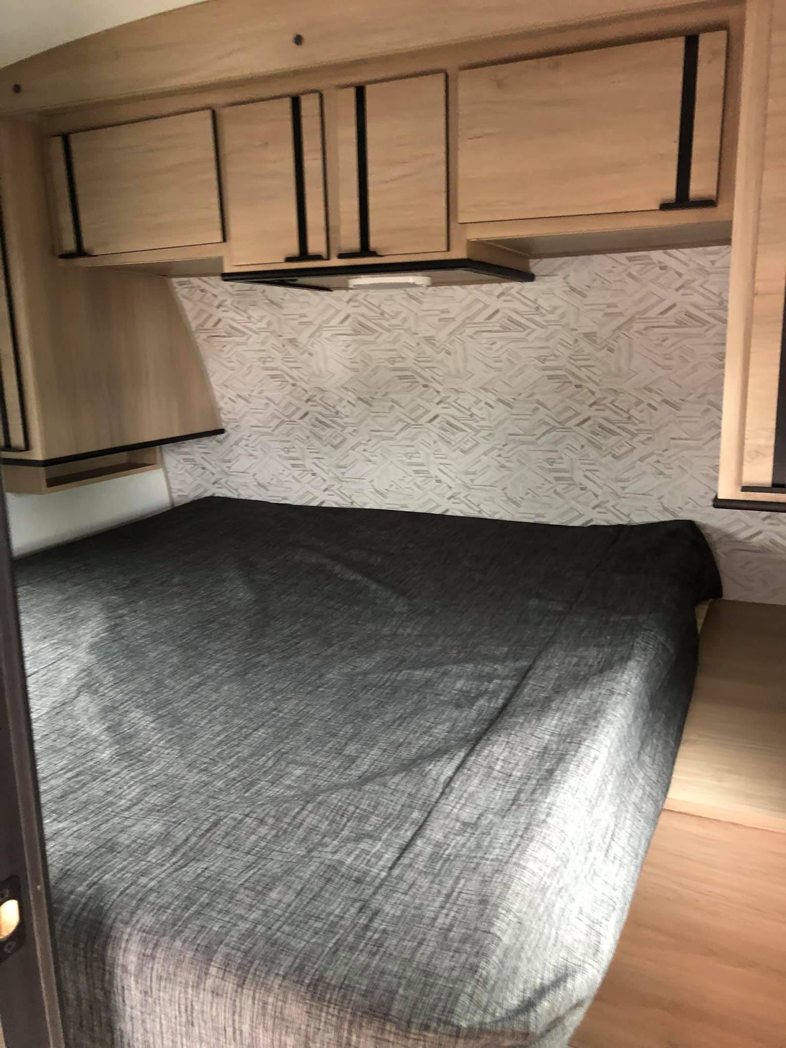 RV rental bedroom: cozy sleeping area with grey bed, overhead cabinets, and patterned wall, perfect for your next trip.. Cruiser Rv Corp Radiance 2021