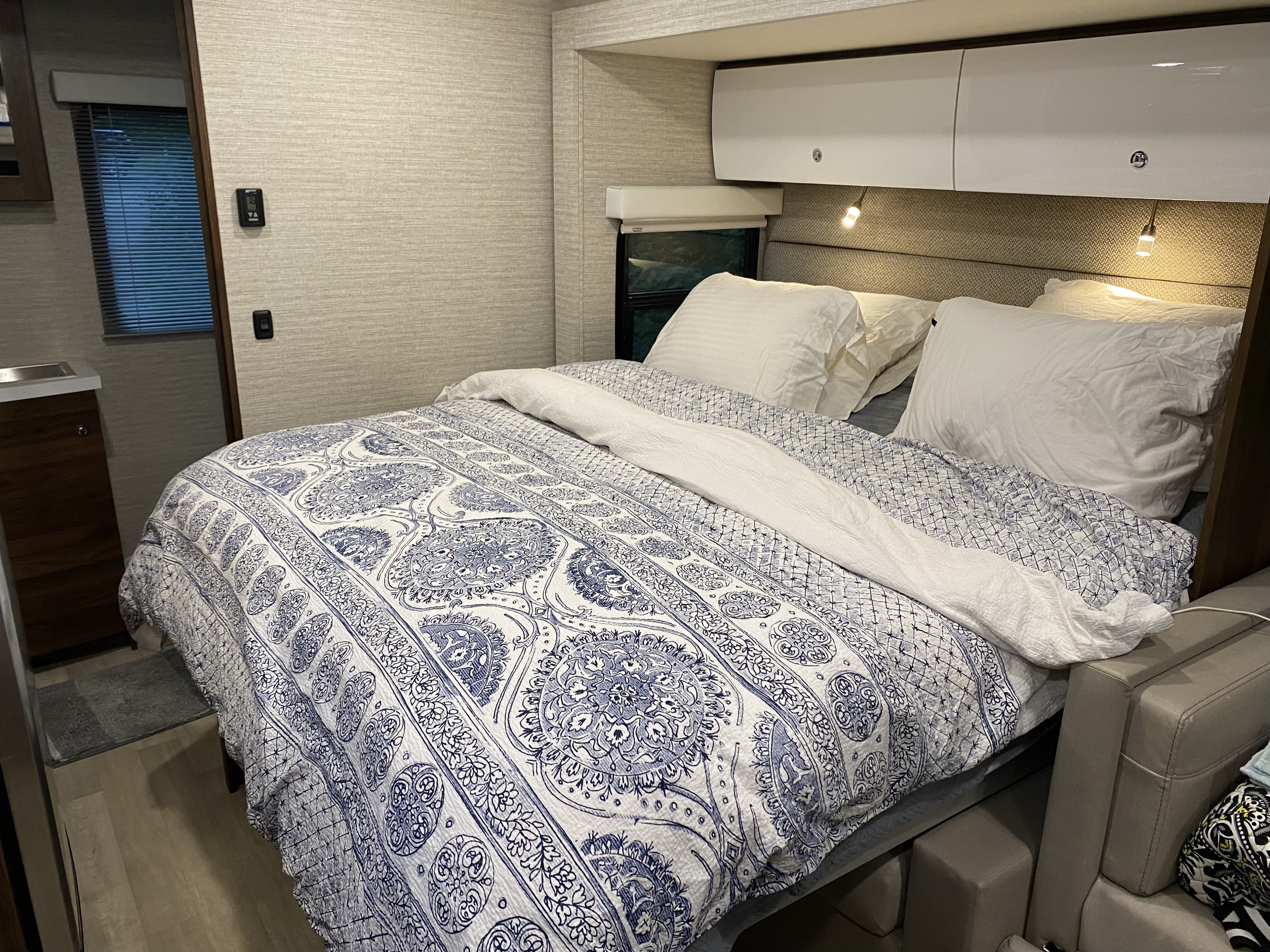 Comfortable RV rental bedroom interior with a blue and white patterned comforter, overhead storage, and compact layout.. Winnebago View 2021