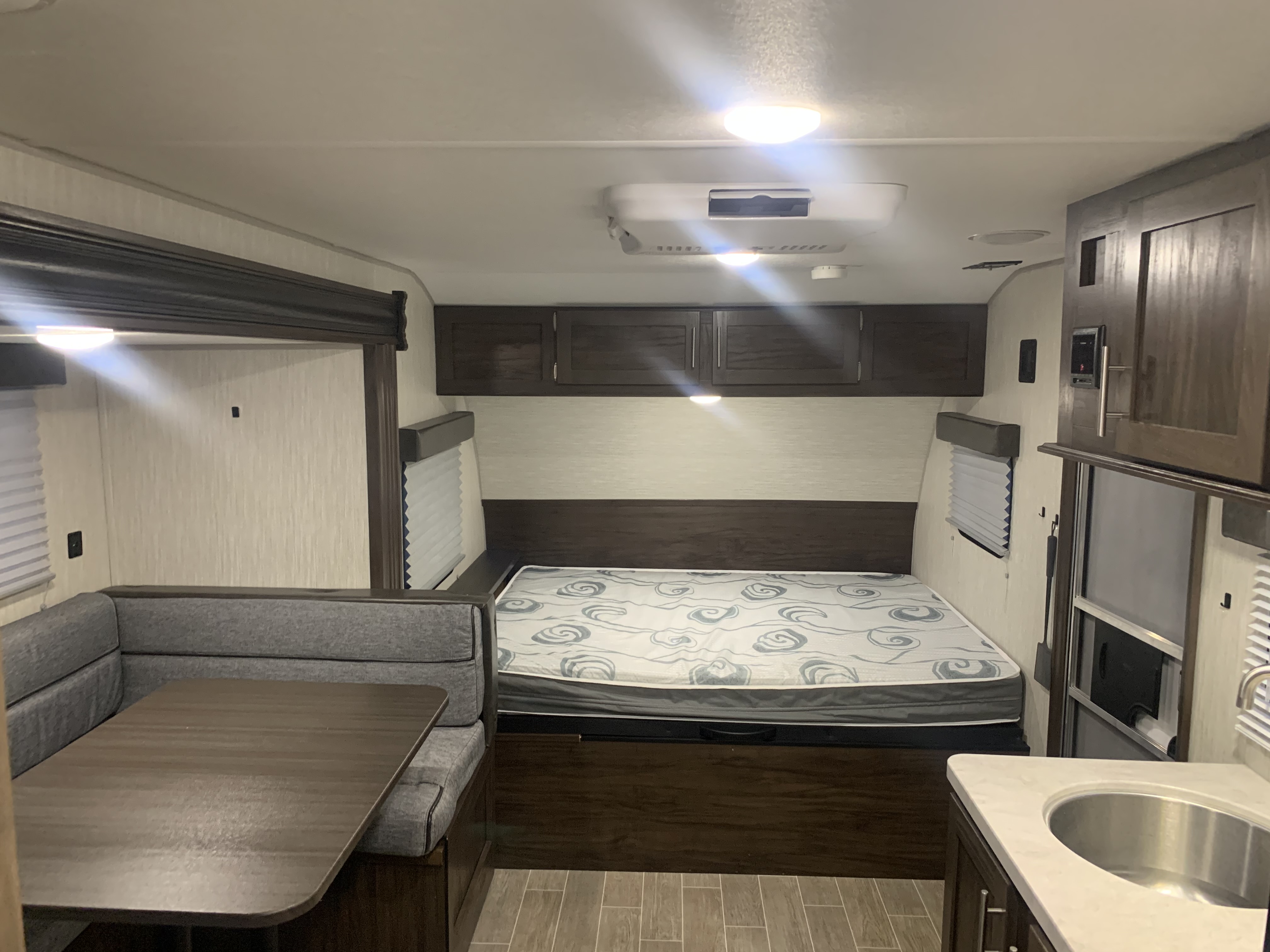 Inside this comfy rv rental: a full bed, U-shaped dinette, and kitchen sink. Ideal for travel adventures and compact living.. Forest River Patriot Edition 2020