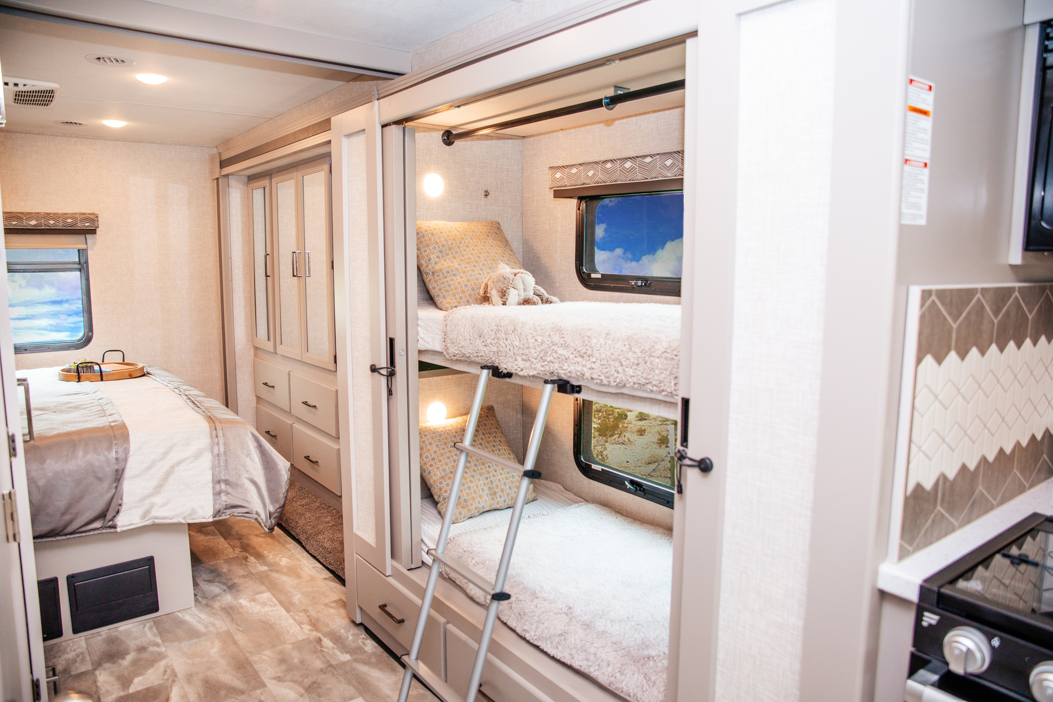 Explore this comfortable RV rental interior featuring a master bed, bunk beds, and kitchenette for your next adventure.. Thor Motor Coach Windsport 2022