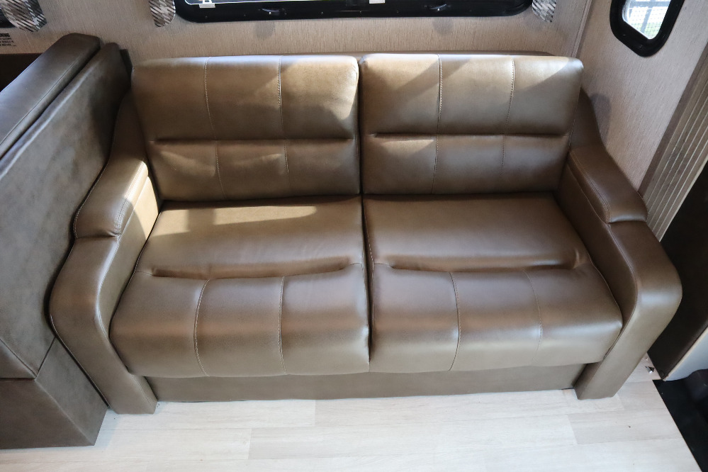 Two-seater tan brown sofa in an RV, featuring tufted cushions; perfect seating for your RV rental.. Nexus Wraith 2022