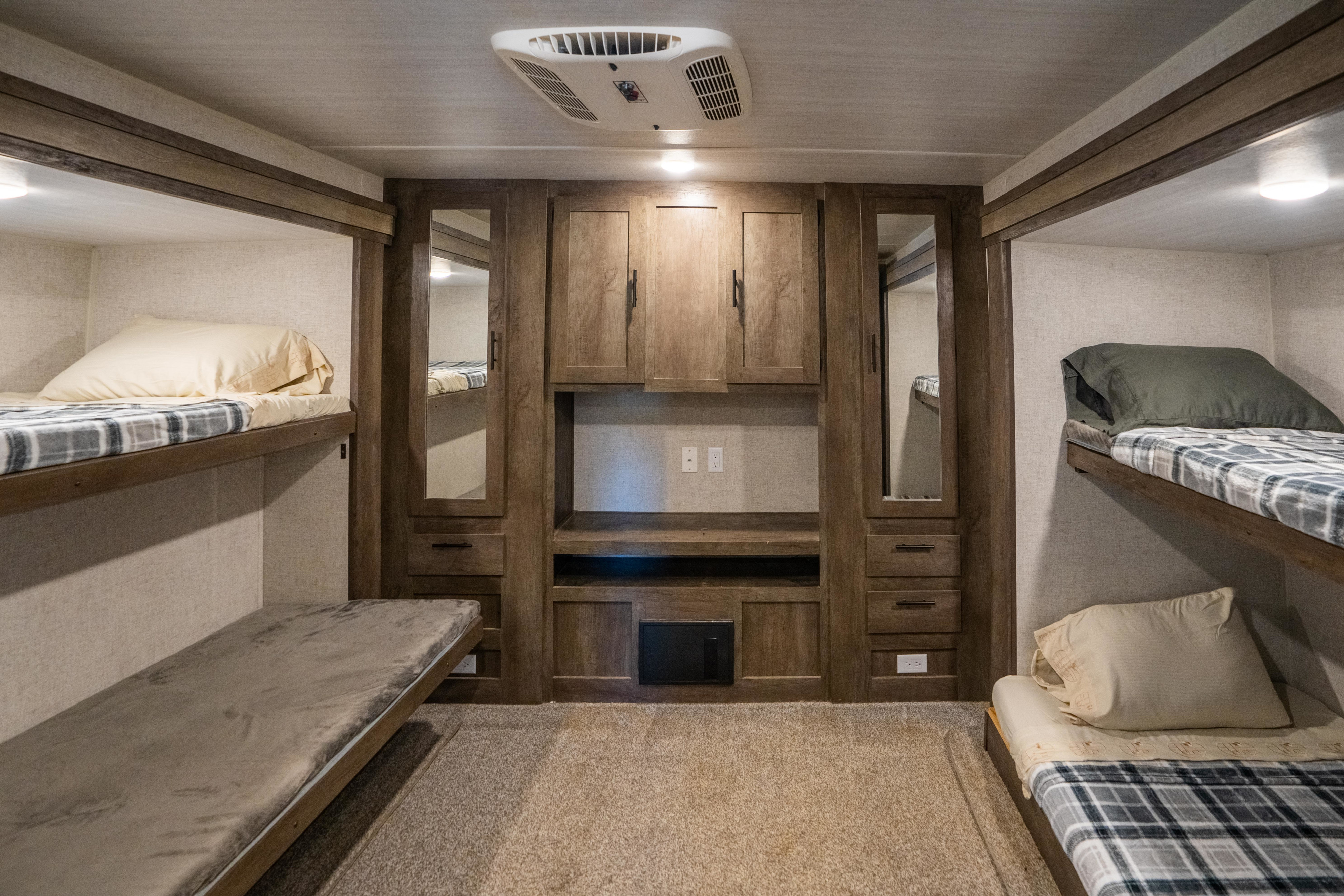 Spacious RV rental bunkhouse interior. Four beds, central storage, mirrored cabinets & AC offer comfort for your next adventure.. Forest River Wildwood 2020