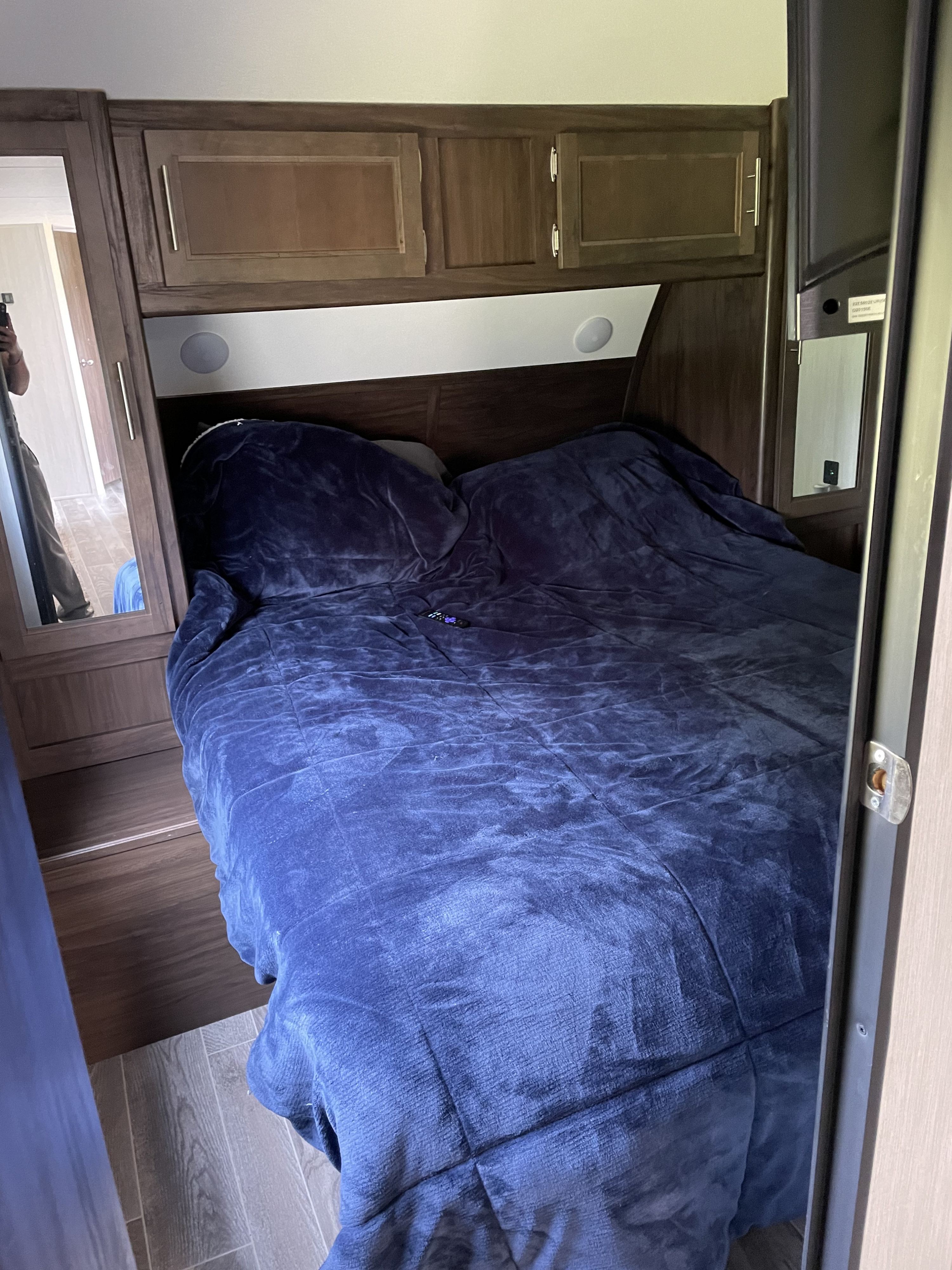 RV rental bedroom: cozy bed with dark blue comforter, wood cabinets, and mirrored closets. Compact, comfortable travel space.. Forest River 264DBH 2019