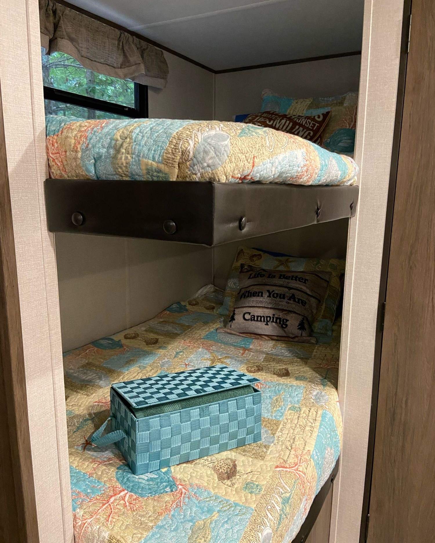 RV rental interior: cozy bunk beds with colorful camping-themed quilts, pillows, and a window view.. Prime Time Avenger 2021