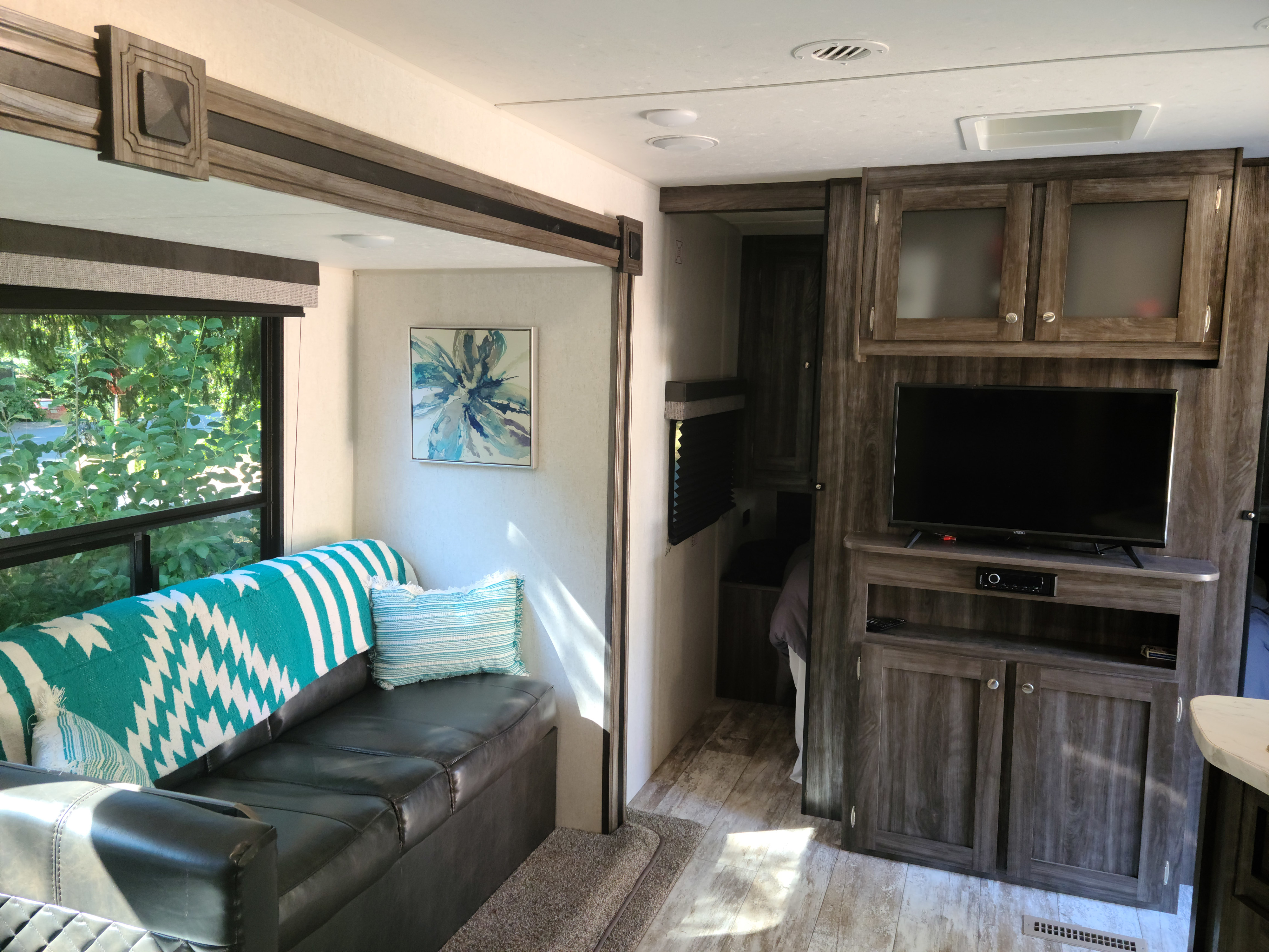 Spacious rv rental interior, featuring a bright living area with sofa, large window, TV, and bedroom access.. Open Range Open Range 2019