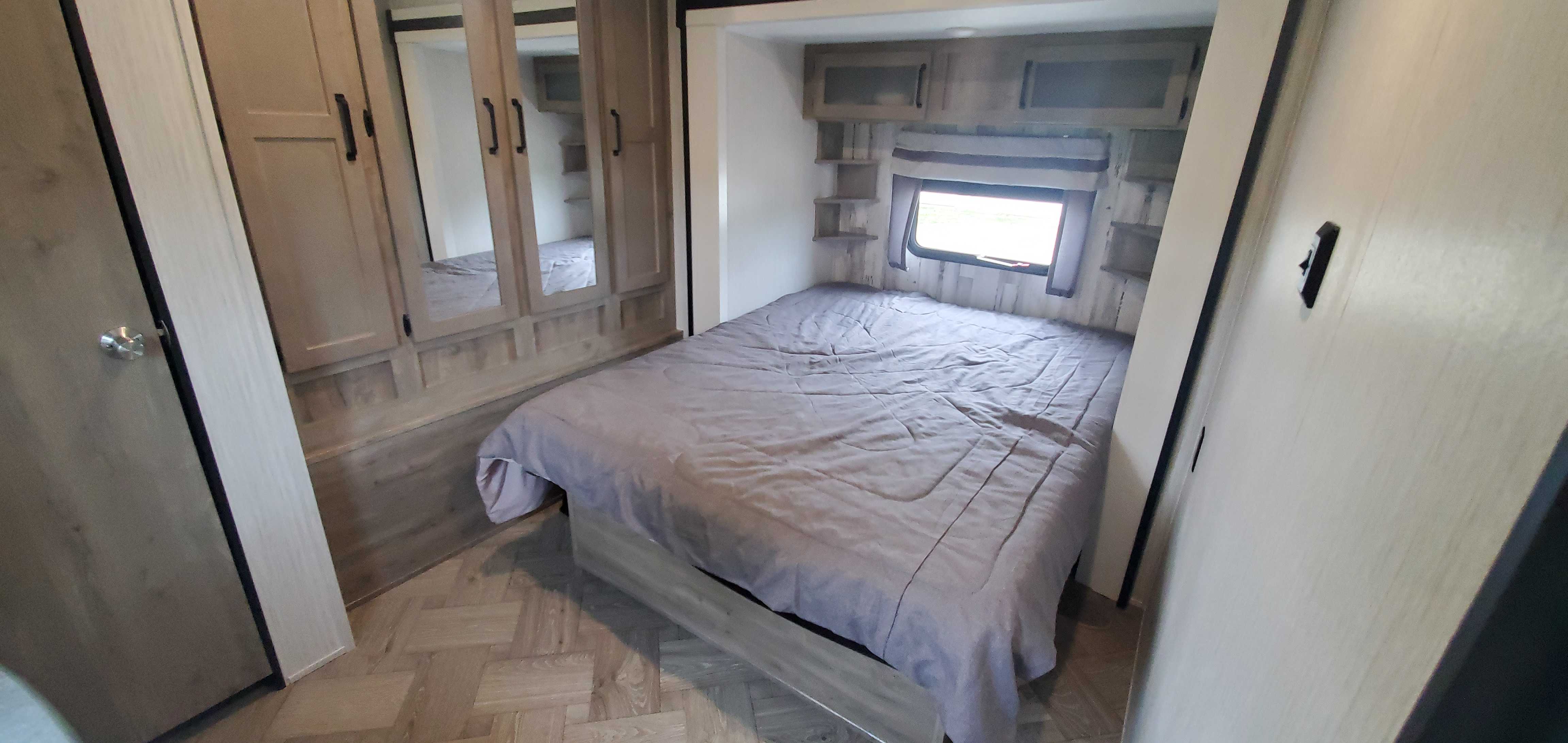 Spacious RV rental bedroom featuring a comfortable bed, mirrored wardrobe, overhead storage, and a window.. Palomino Puma 2021